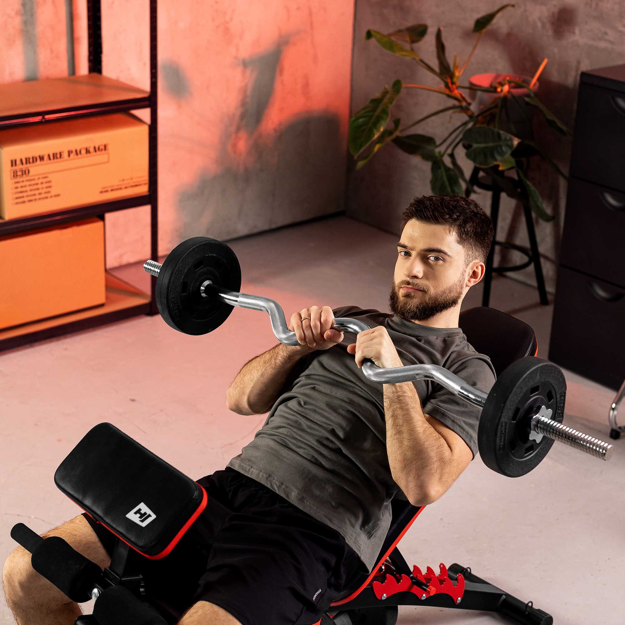 Ein Mann hebt in einem Fitnessstudio eine Langhantel auf einer Schrägbank.