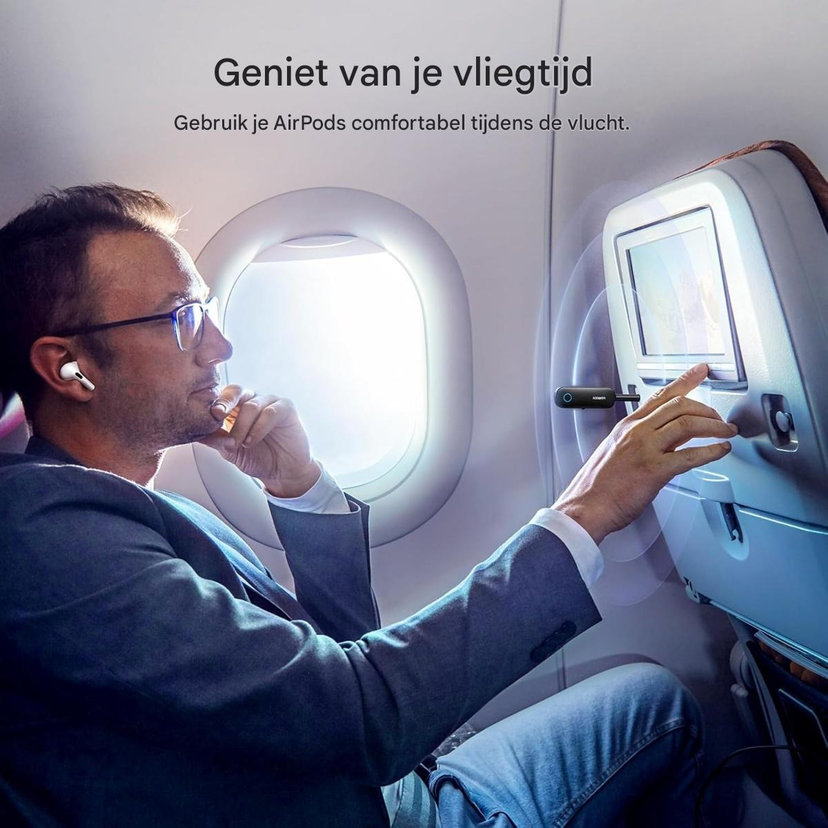 Ein Mann mit kabellosen Ohrstöpseln und Brille bedient einen Bildschirm im Flugzeug.