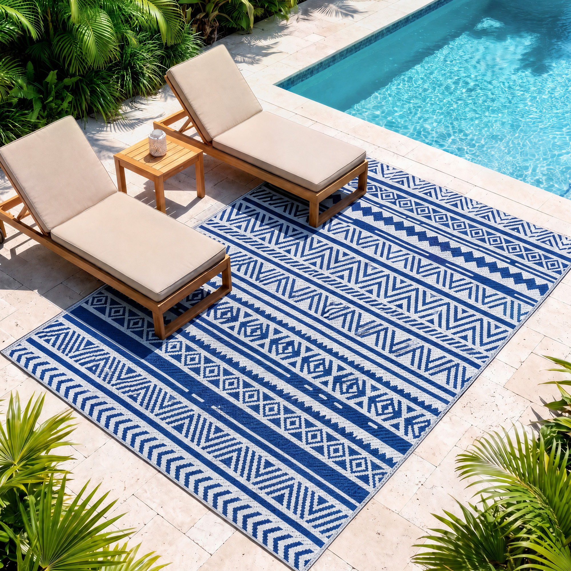 Dos tumbonas beiges sobre una alfombra azul con patrón junto a una piscina y plantas.
