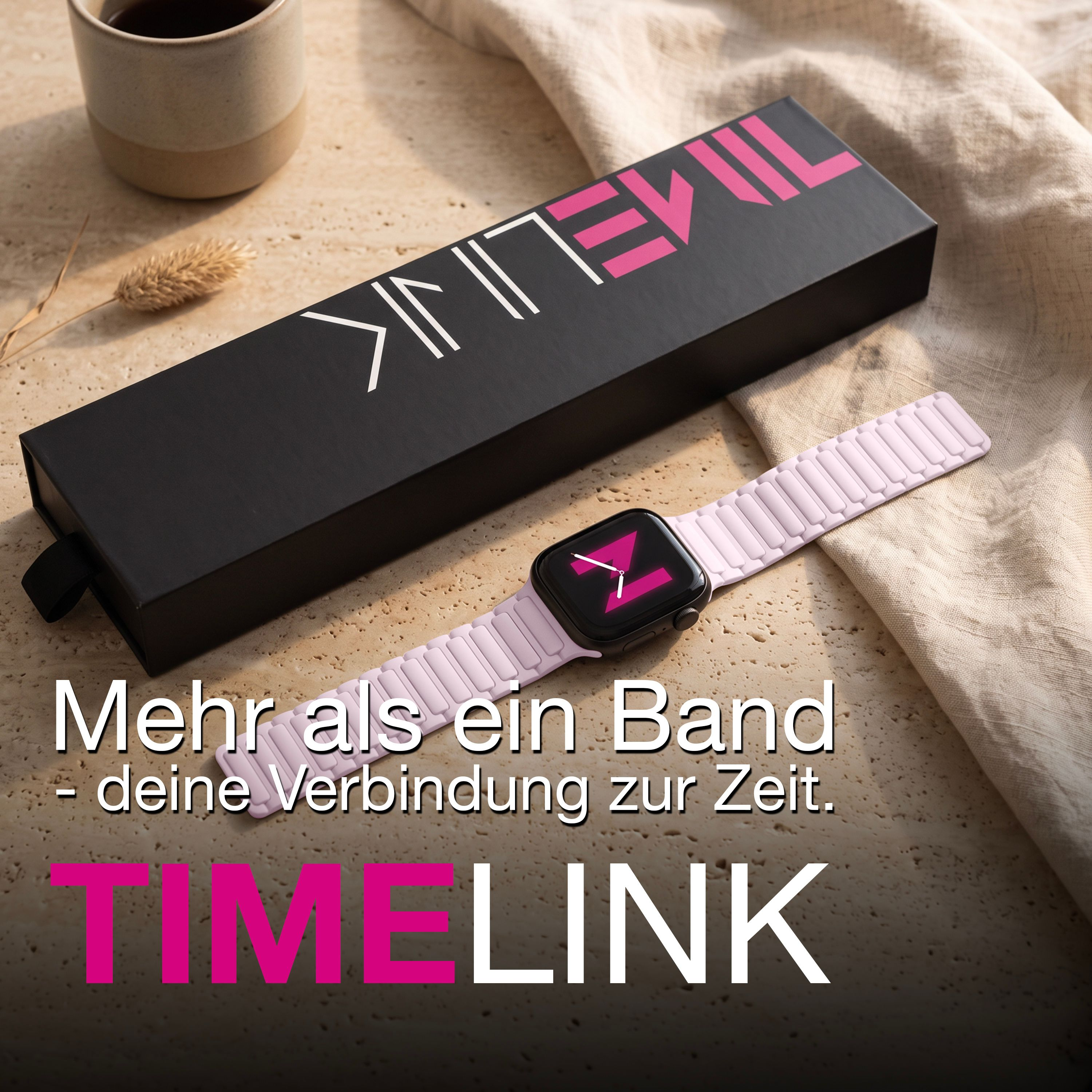 Eine Smartwatch mit rosa Armband liegt neben einer schwarzen Box, einer Tasse und Stoff auf hellem Untergrund.