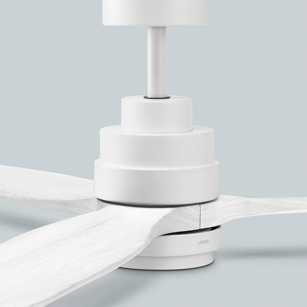 Primo piano di un ventilatore da soffitto bianco con pale in legno su sfondo grigio chiaro.