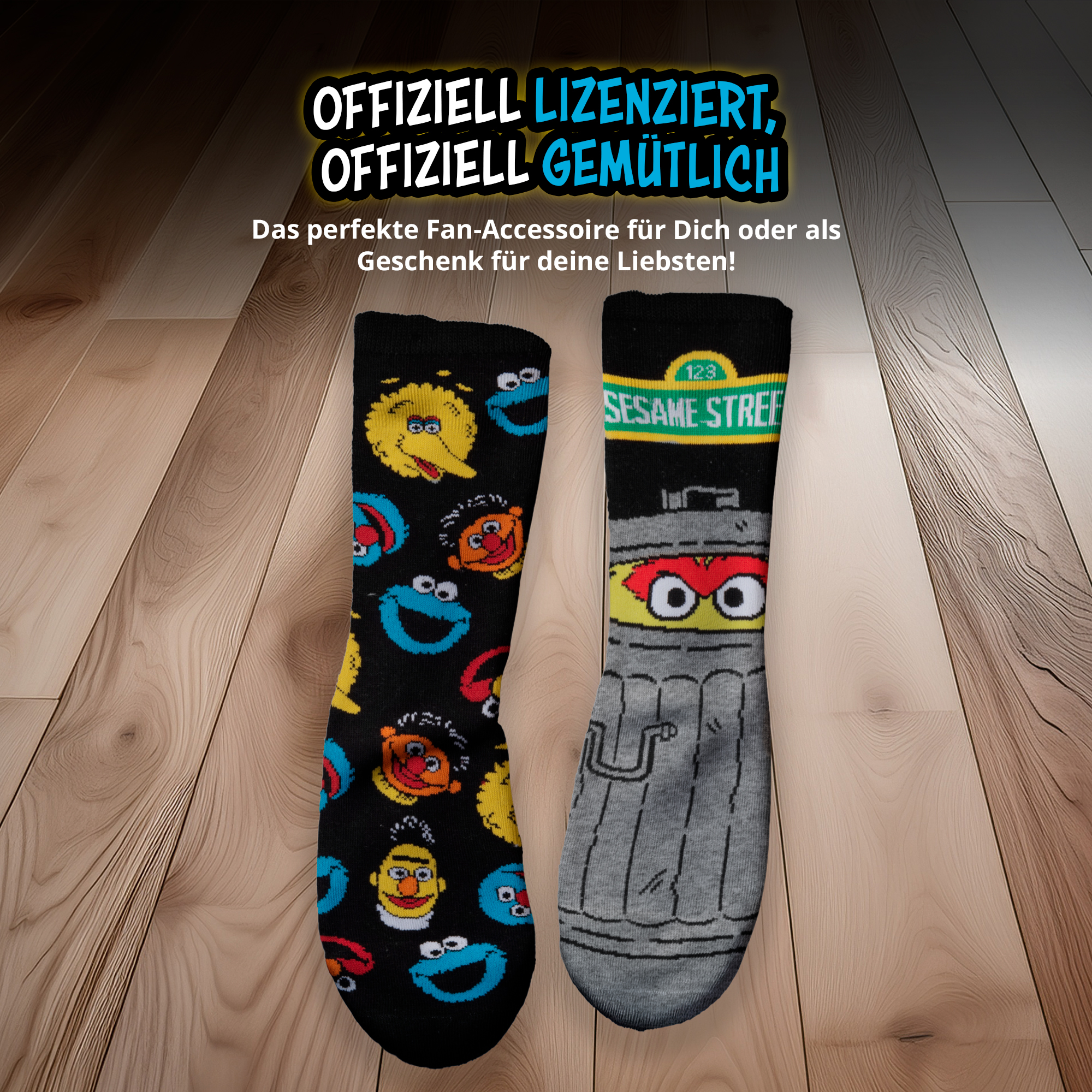 Zwei schwarze Sesamstraße-Socken mit Charakteren auf Holzfußboden und deutscher Werbeinschrift.