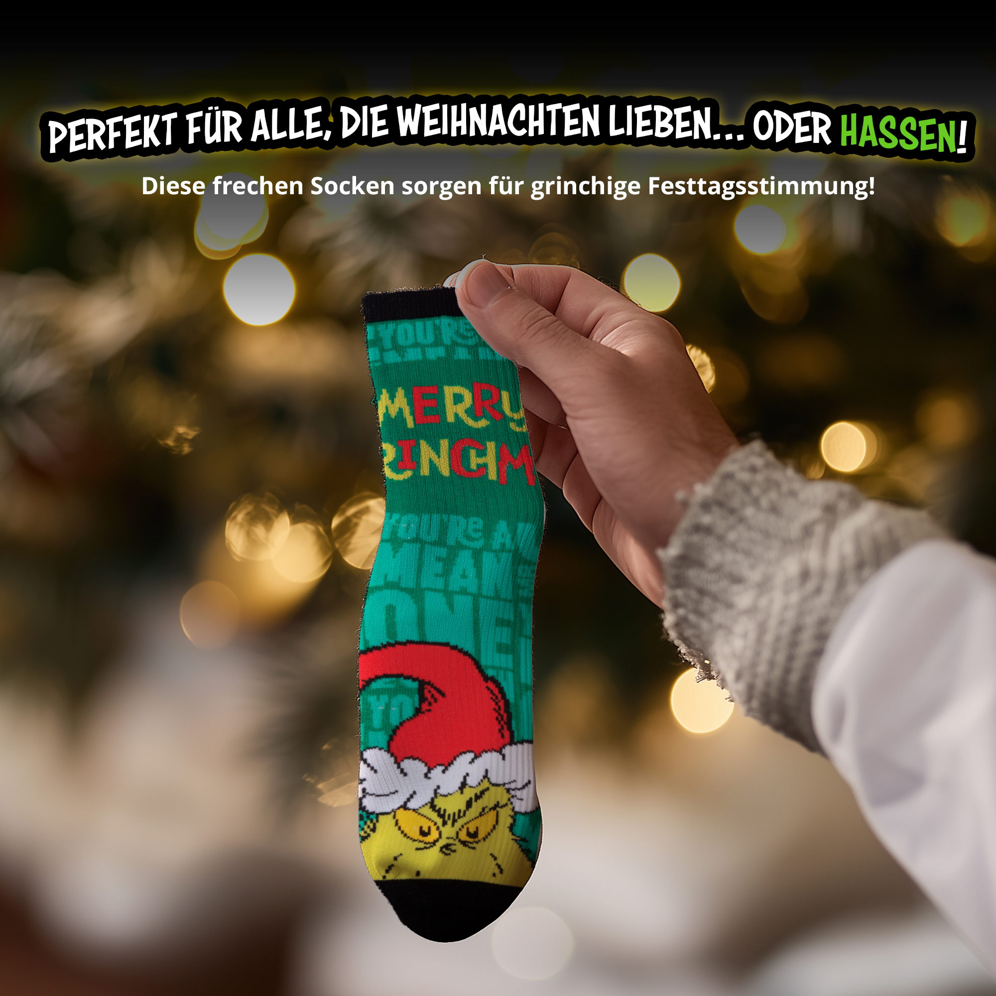 Hand hält grüne Weihnachtssocke mit dem Grinch und Text, vor Weihnachtsbaum.