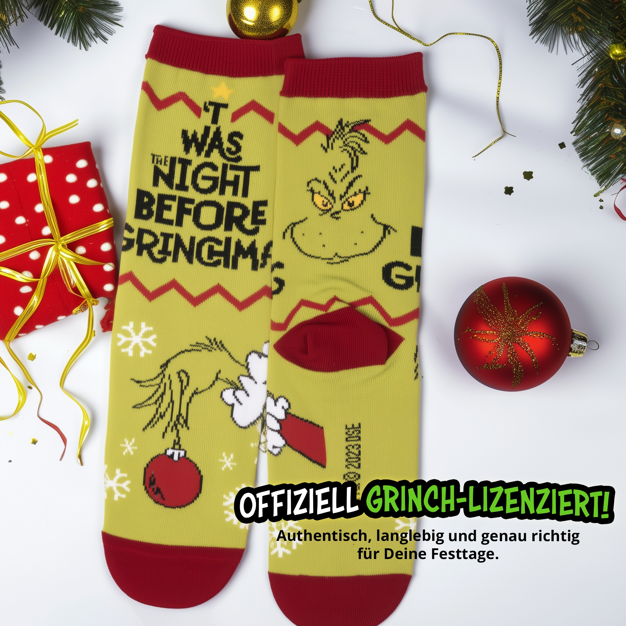 Gelbe Grinch Weihnachtssocken mit rotem Rand, Text und Ornamenten auf weißem Untergrund mit Geschenk.