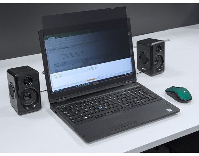 Laptop z filtrem prywatności, dwoma czarnymi głośnikami i zieloną myszą na białym biurku.
