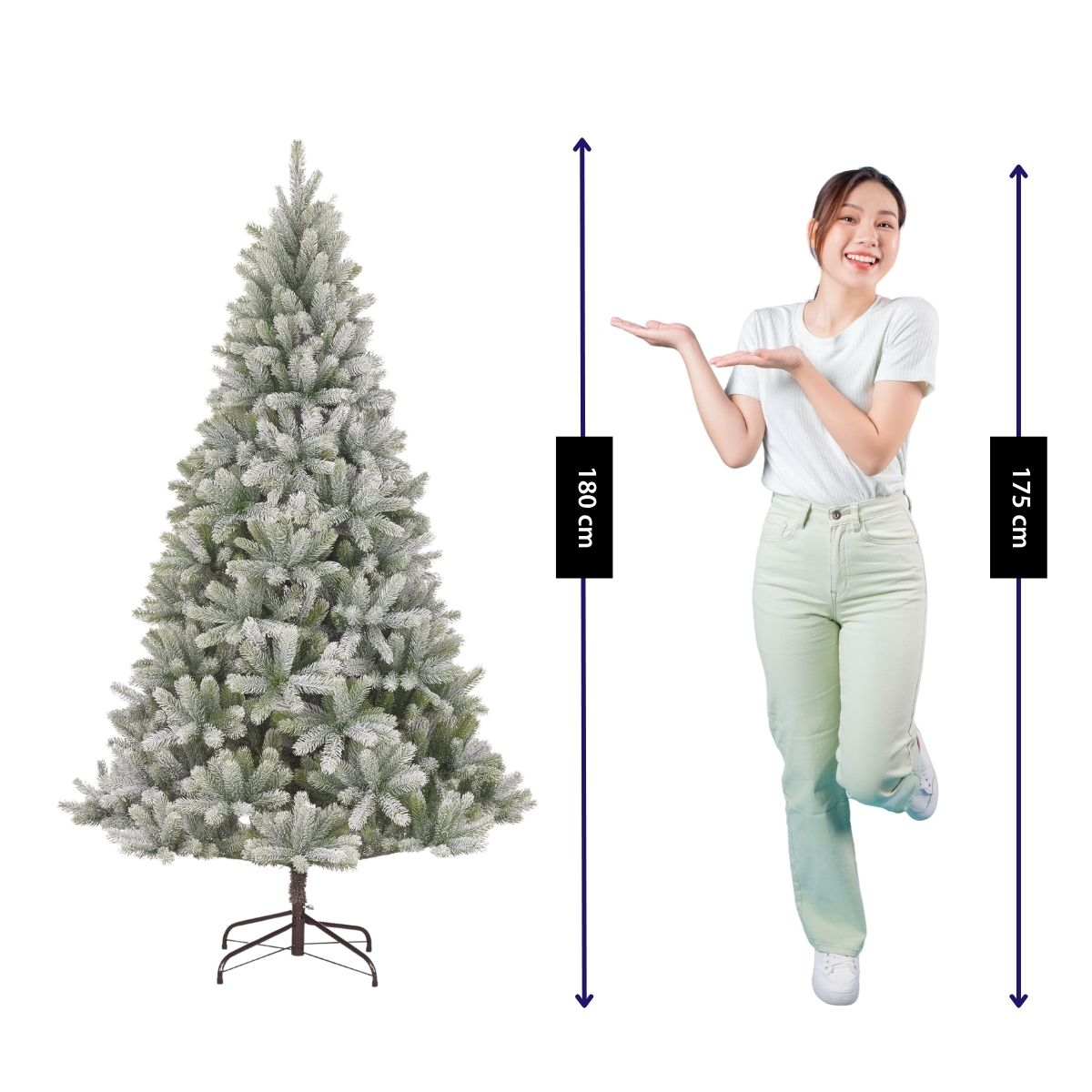 Een vrouw in een wit shirt presenteert een 180 cm hoge kunstkerstboom met sneeuw.