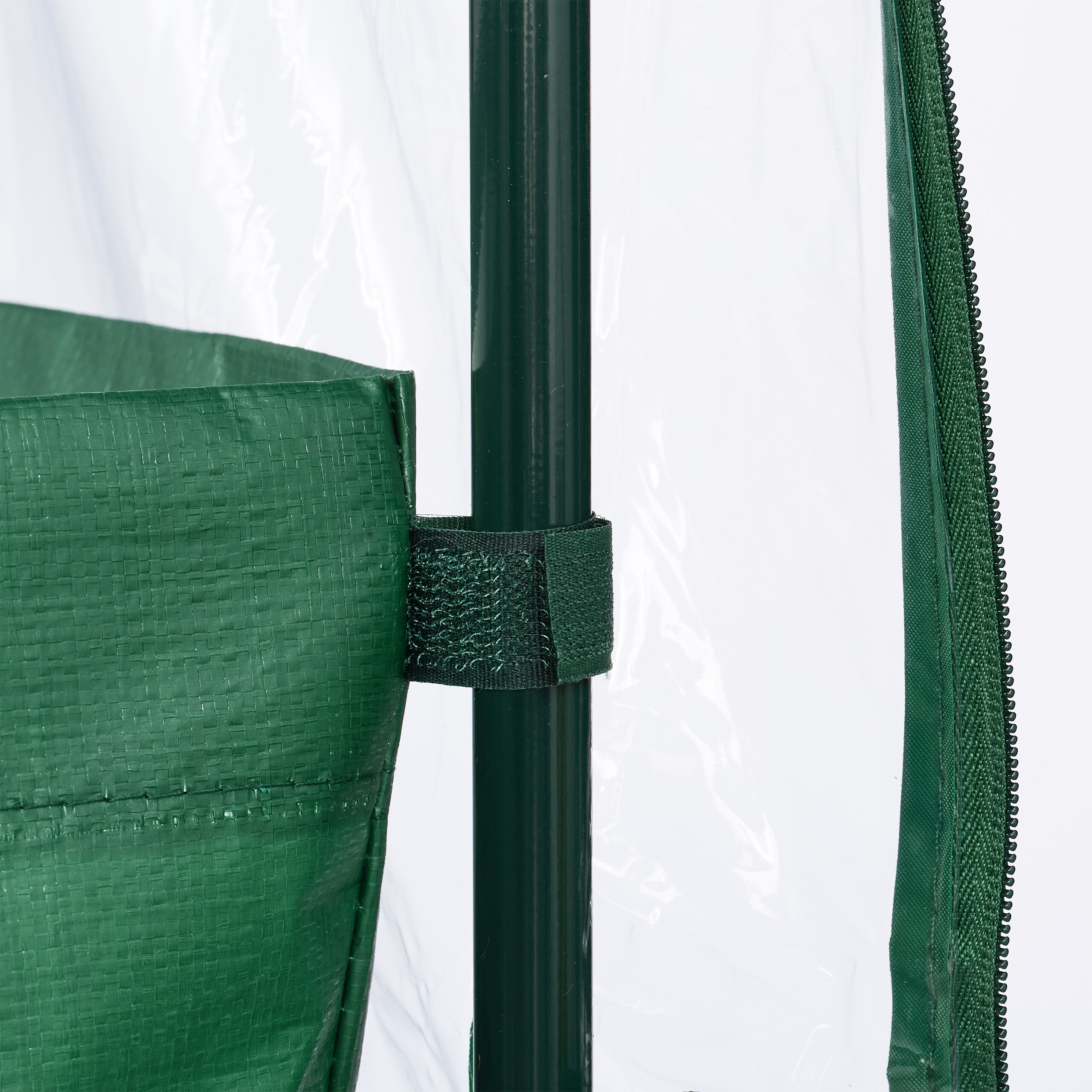 Grüne Gewächshaustasche befestigt mit Klettverschluss an einem Stab vor klarer Folie.