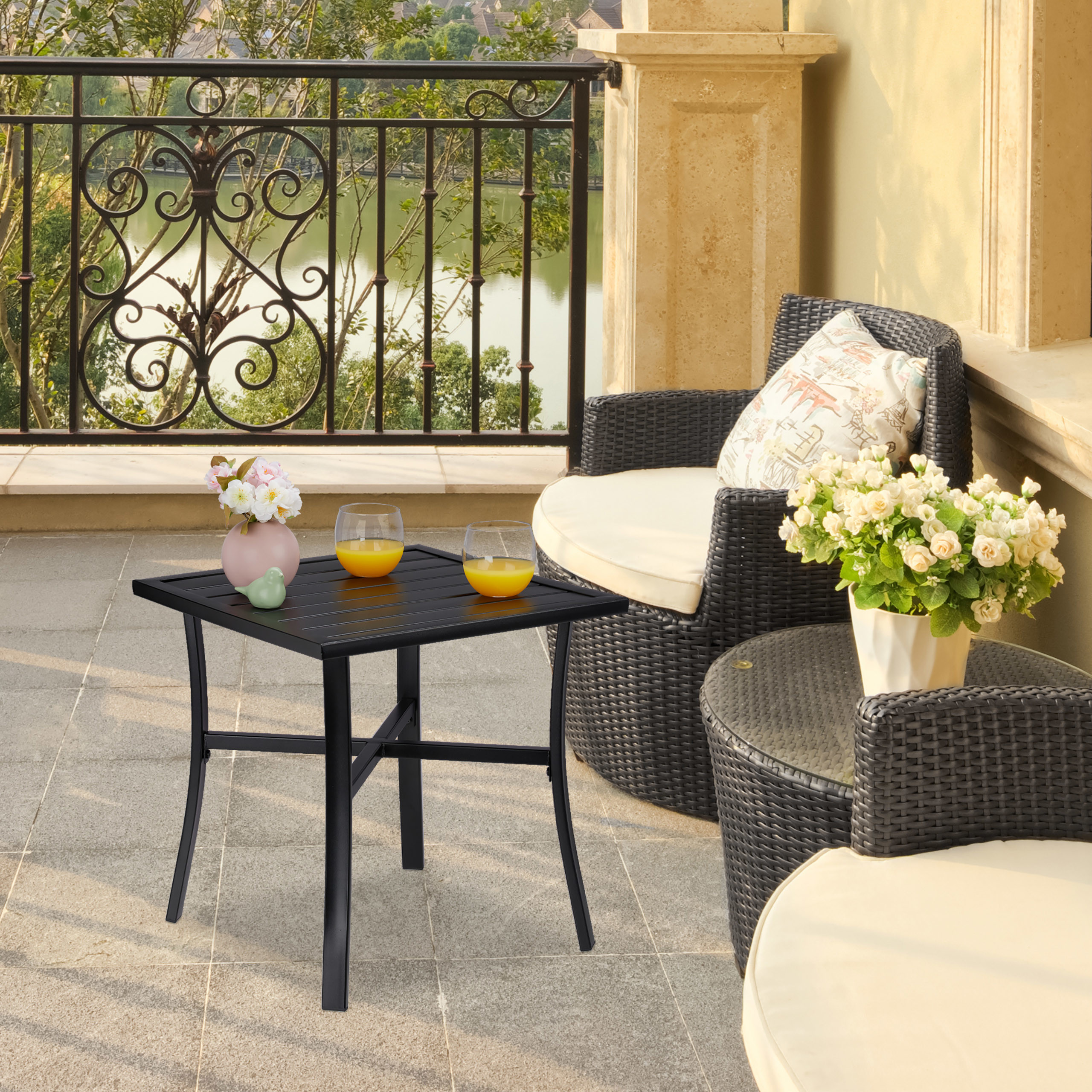 Ein Balkon mit Rattanmöbeln, einem Tisch mit Orangensaft und Blumen, mit Blick auf einen See.