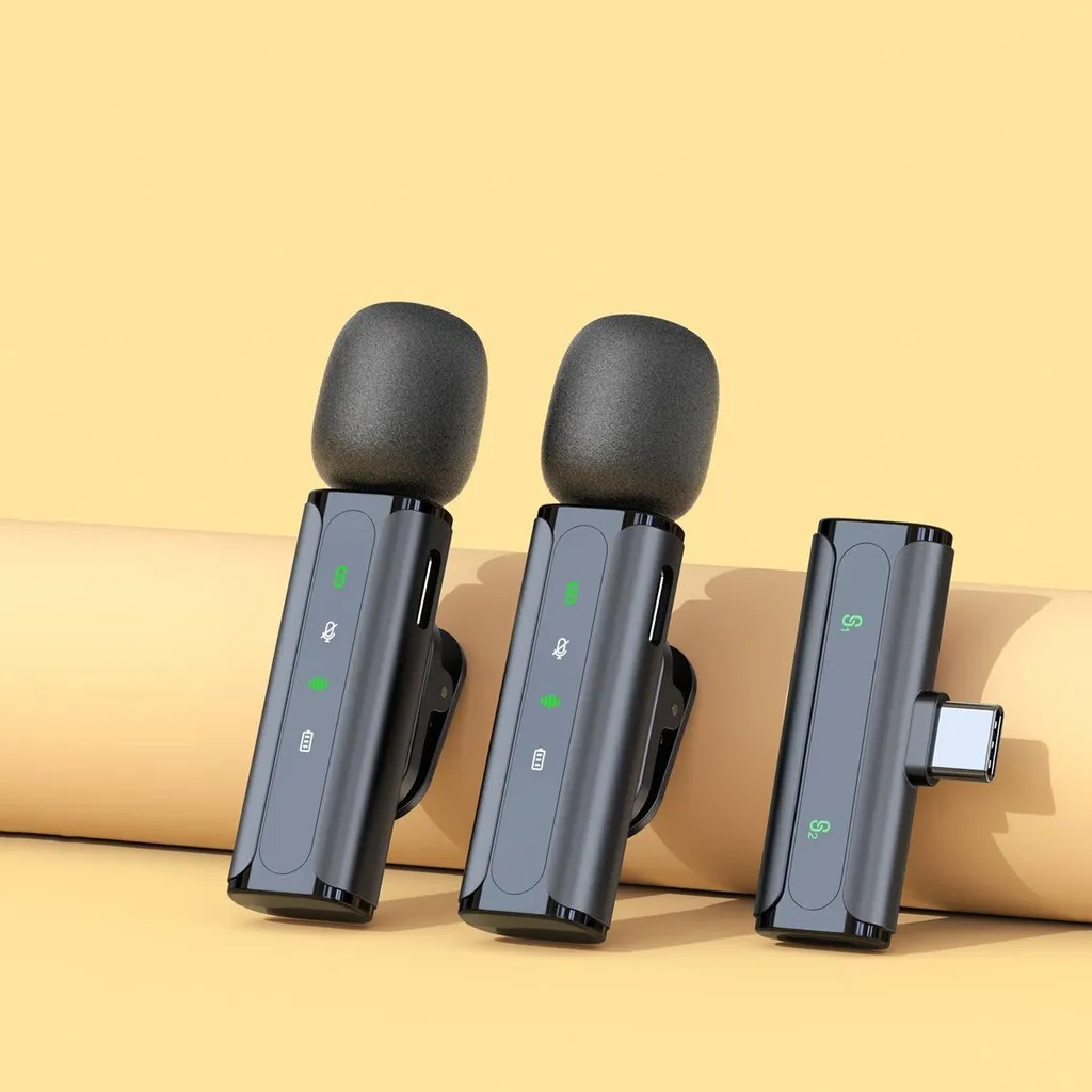 Zwei schwarze Lavallier-Mikrofone mit Windschutz und ein Empfänger mit USB-C-Stecker vor einem gelben Hintergrund.