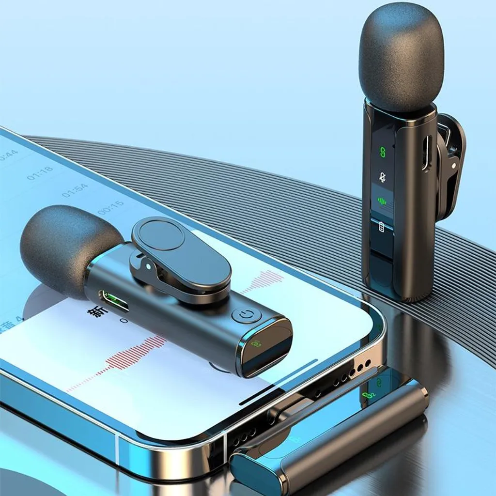 Drei schwarze kabellose Ansteckmikrofone neben einem Smartphone auf glänzender Oberfläche.