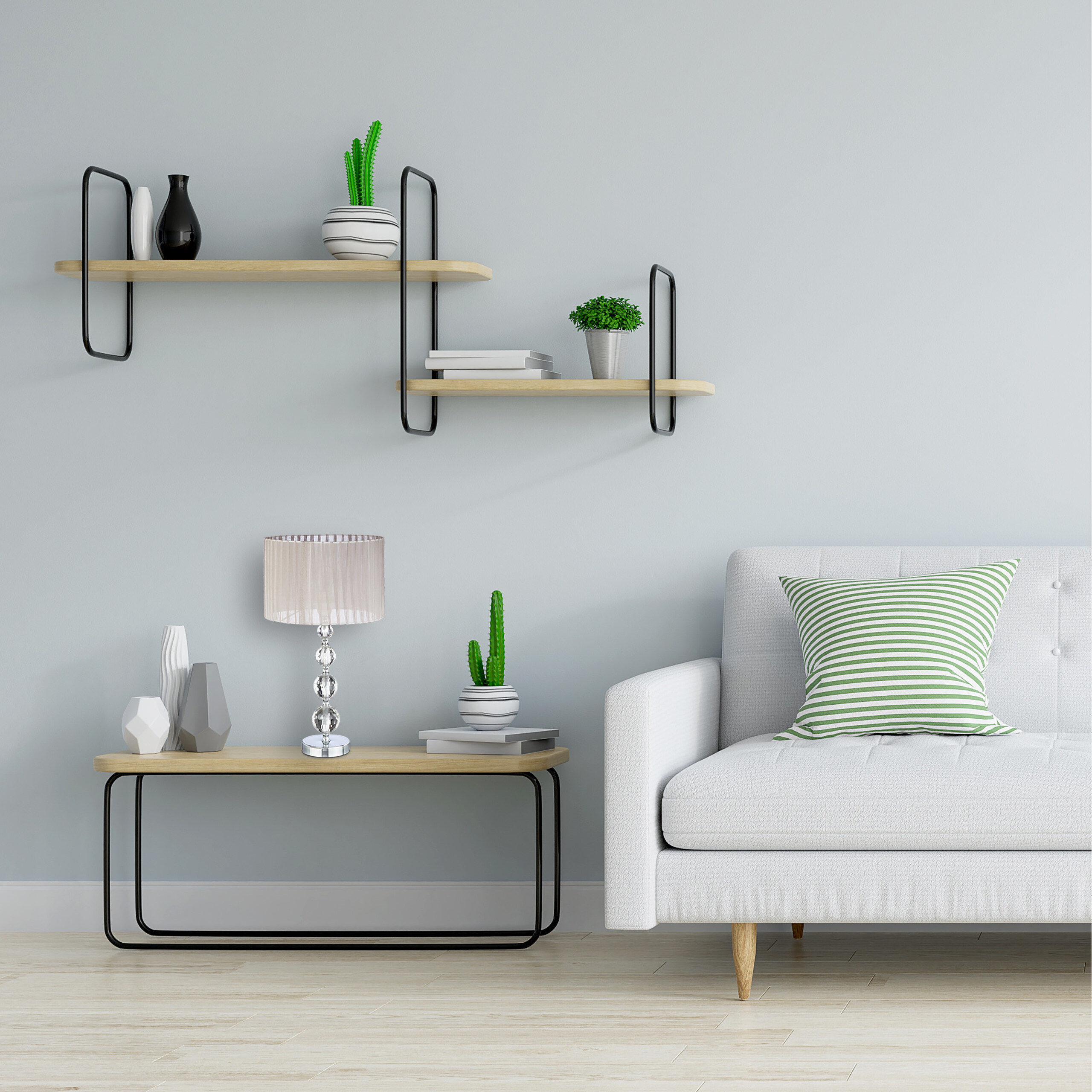 Ein weißes Sofa mit grünem Kissen, ein Couchtisch mit Lampe und Kaktus sowie Regale mit Vasen vor grauer Wand.
