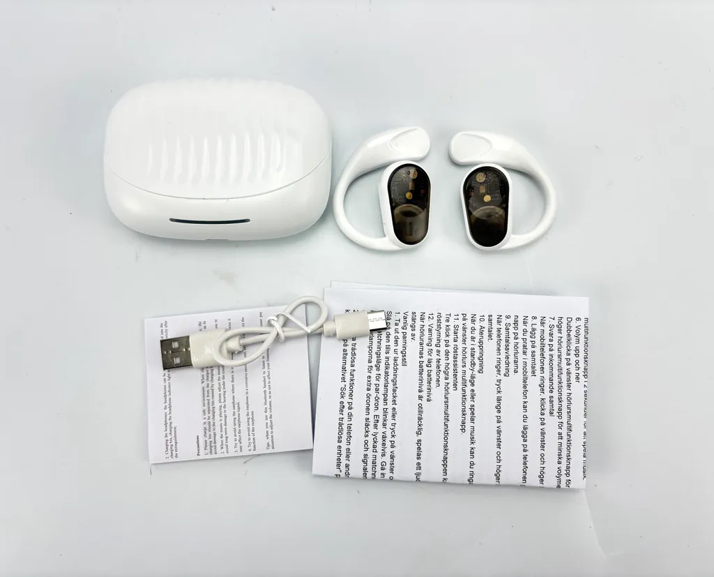 Weiße drahtlose Ohrhörer mit Ladecase, USB-Kabel und Anleitung.