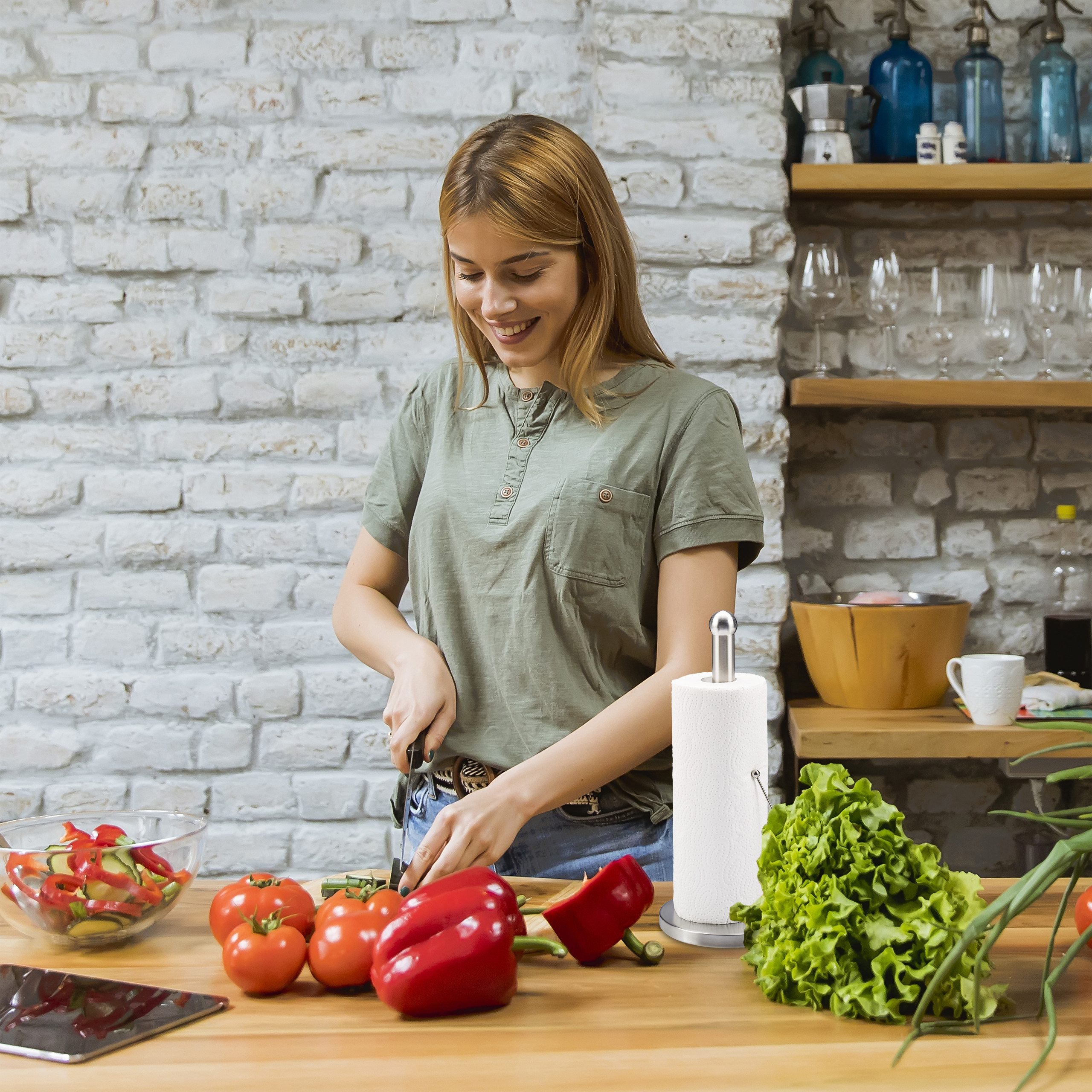 Eine Frau schneidet Tomaten und Paprika in einer Küche mit Ziegelwand und Holzregalen.