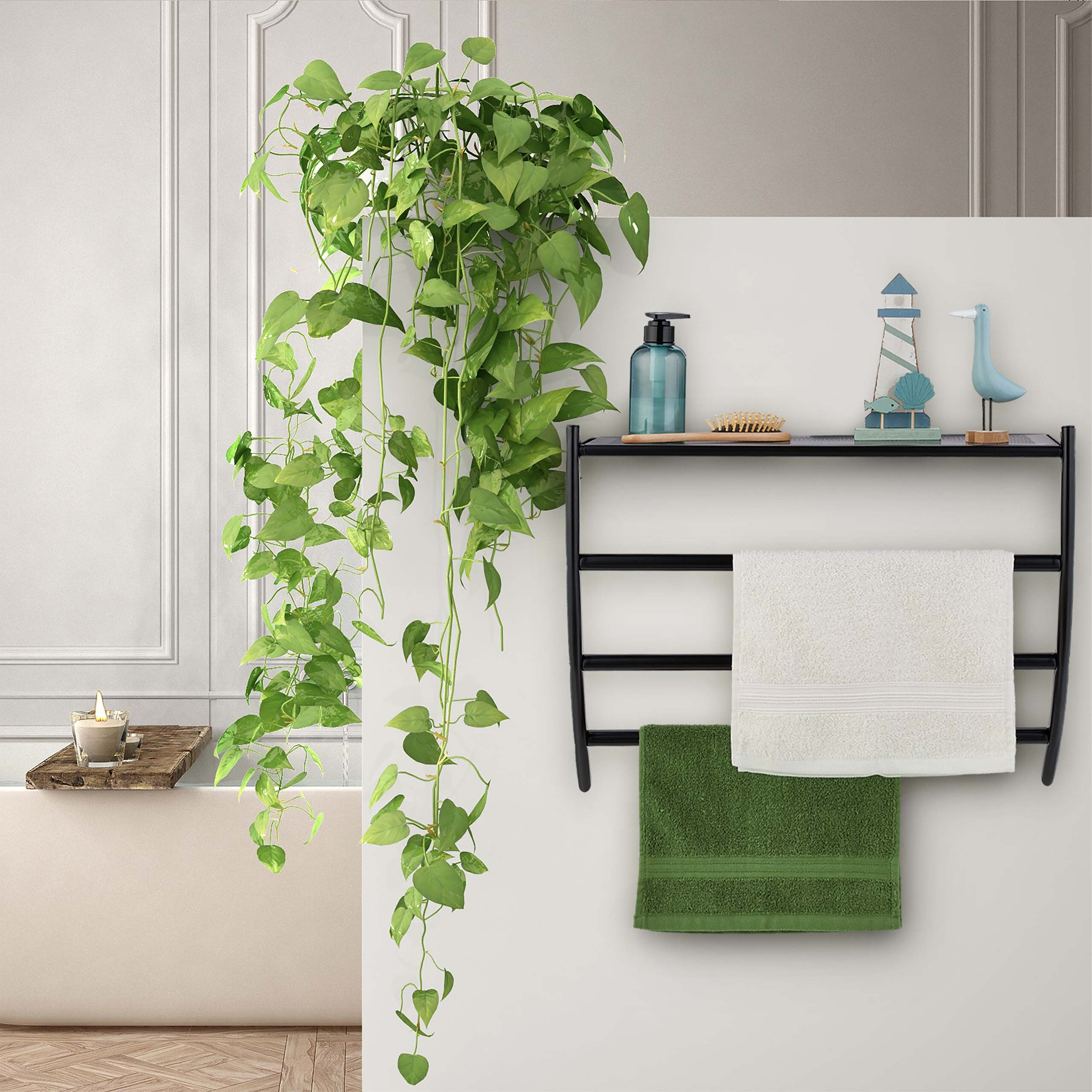 Badezimmer mit schwarzem Metallregal an der Wand, hängender grüner Pflanze, Seifenspender und Handtüchern.