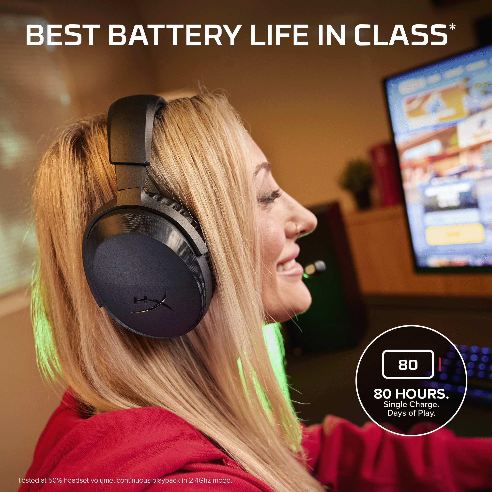 Blonde Frau in rotem Pullover trägt schwarzes Headset vor einem Monitor.