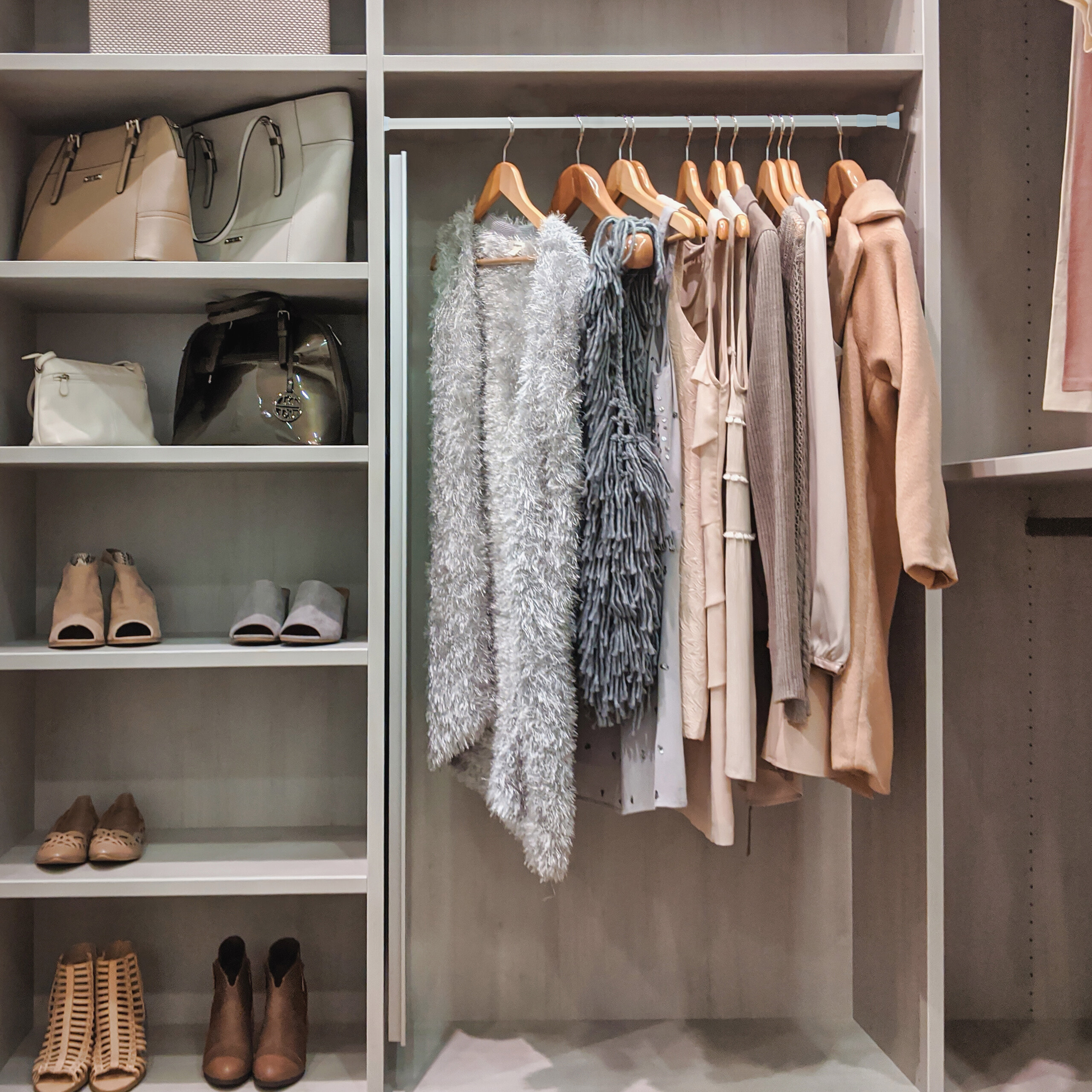 Ein gut organisierter begehbarer Kleiderschrank mit Handtaschen, Schuhen und hängender Kleidung.