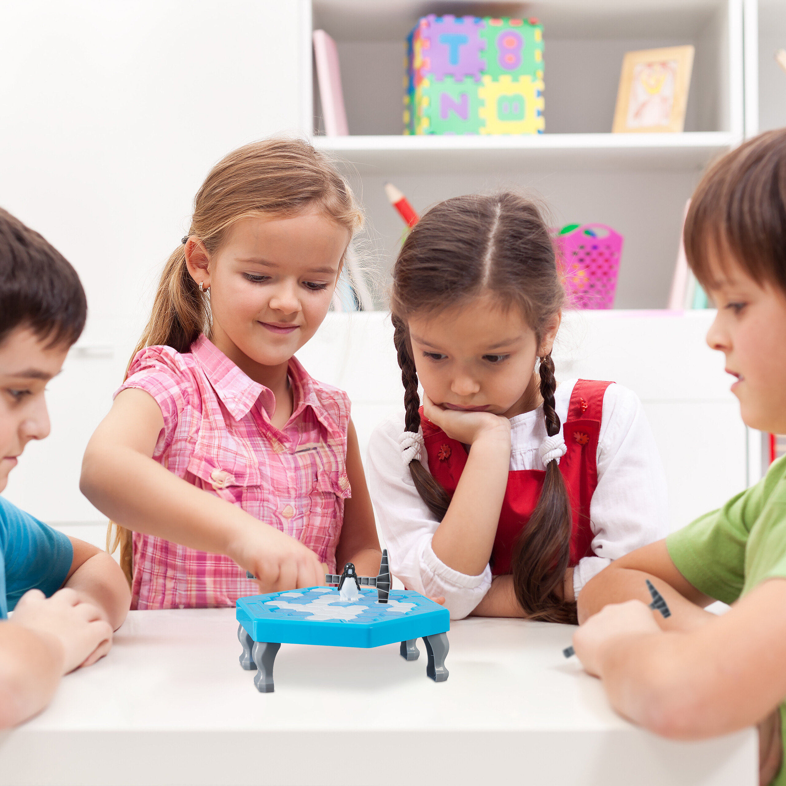 Vier Kinder spielen zusammen an einem Tisch ein blaues Eisschollenspiel.