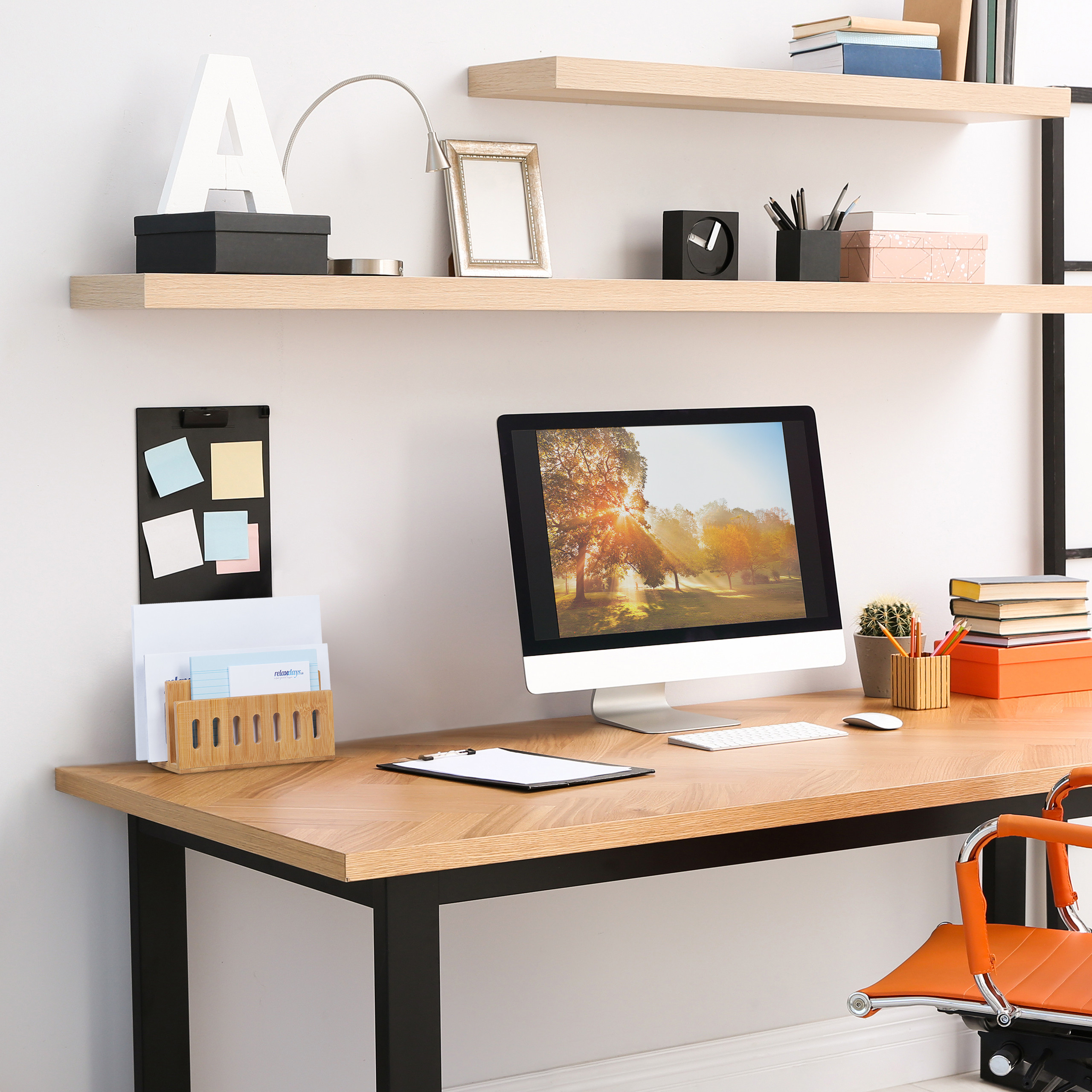 Moderne Arbeitsplatz mit einem Computer auf einem Holztisch, an der Wand befestigte Regale und orangefarbenem Stuhl.