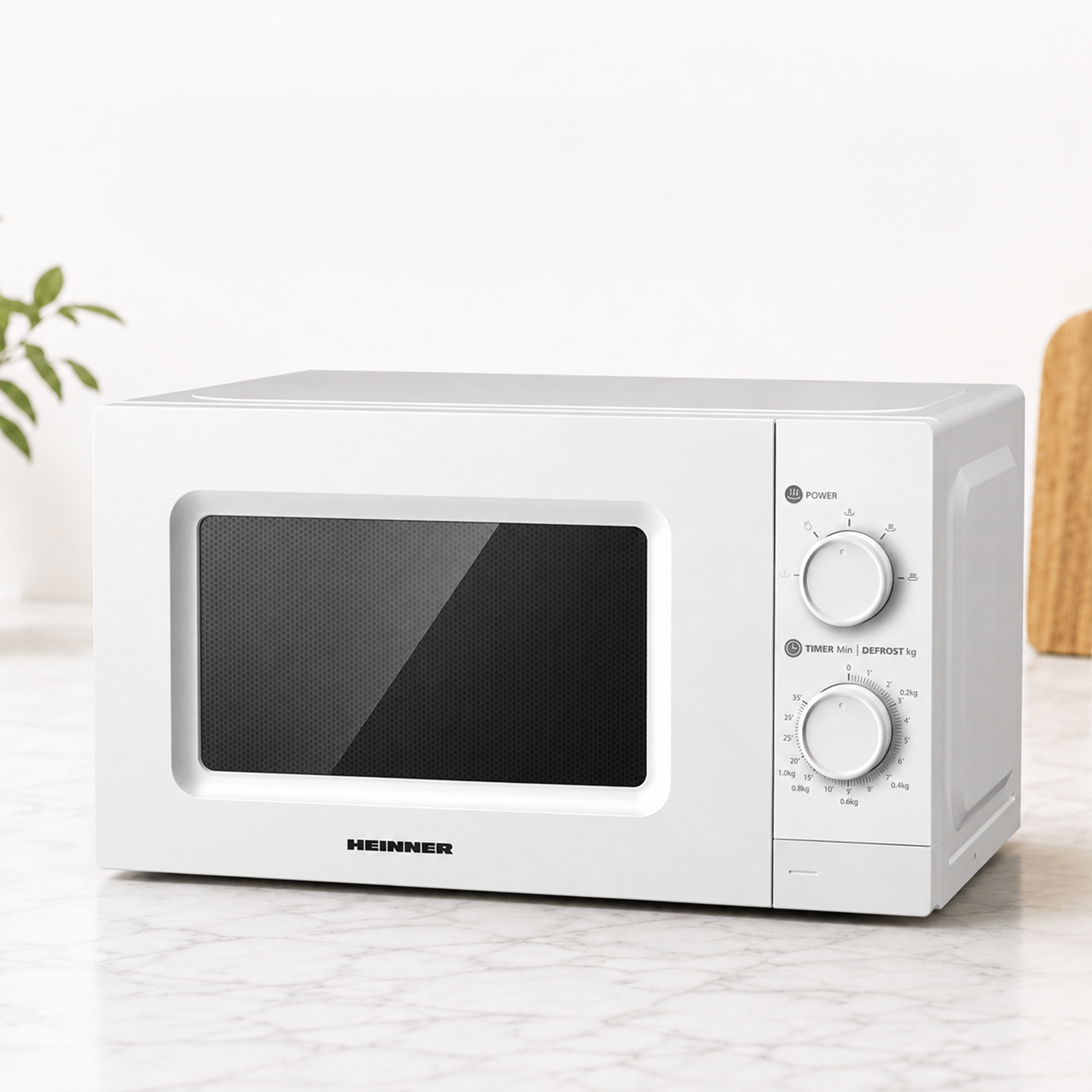 A white Heinner microwave sits on a marble countertop in a bright kitchen.