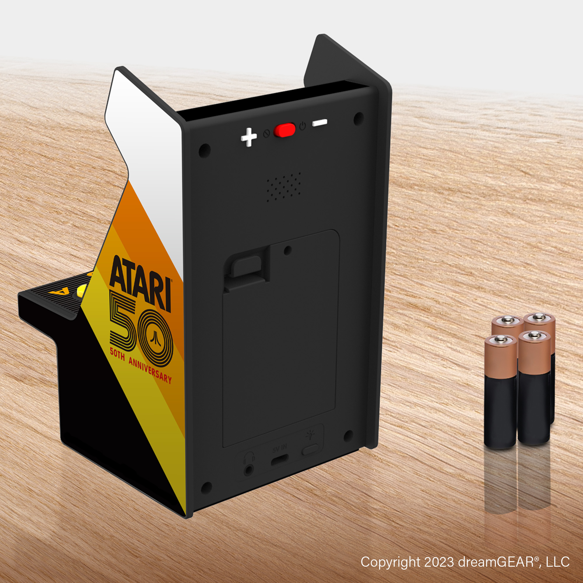 Rückansicht des Atari 50 Arcade-Gehäuses mit vier Batterien auf Holztisch.