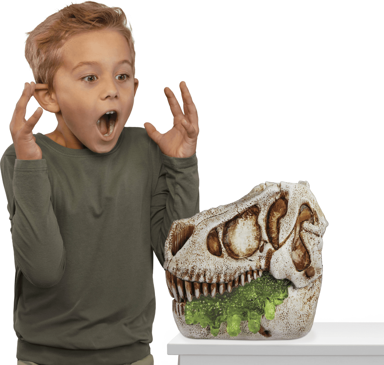 Un niño sorprendido mira una calavera de dinosaurio con baba verde goteando de su boca.