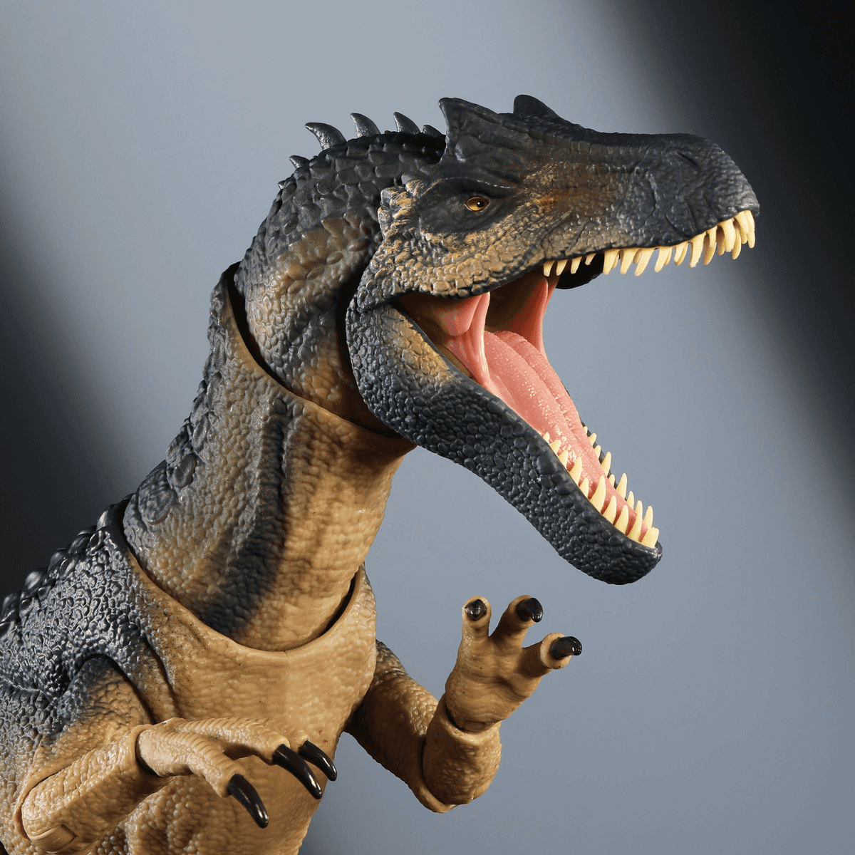 Dettagliata action figure di un dinosauro grigio scuro con bocca aperta, denti aguzzi e artigli su sfondo grigio.