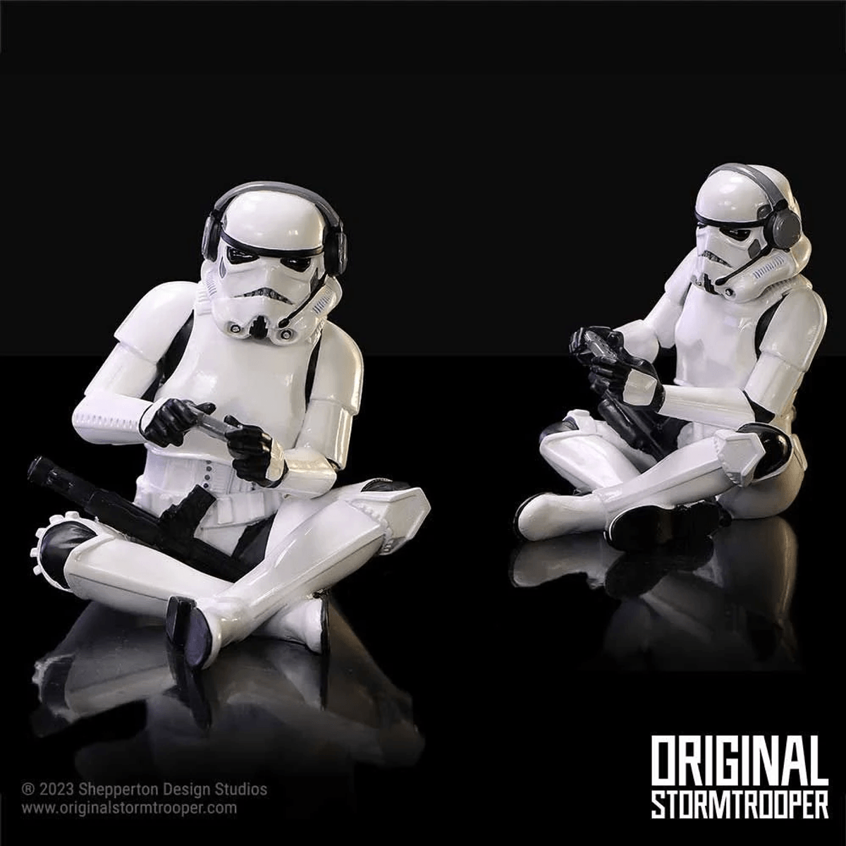 Dos figuras blindadas de Stormtrooper se sientan en el suelo jugando con mandos.