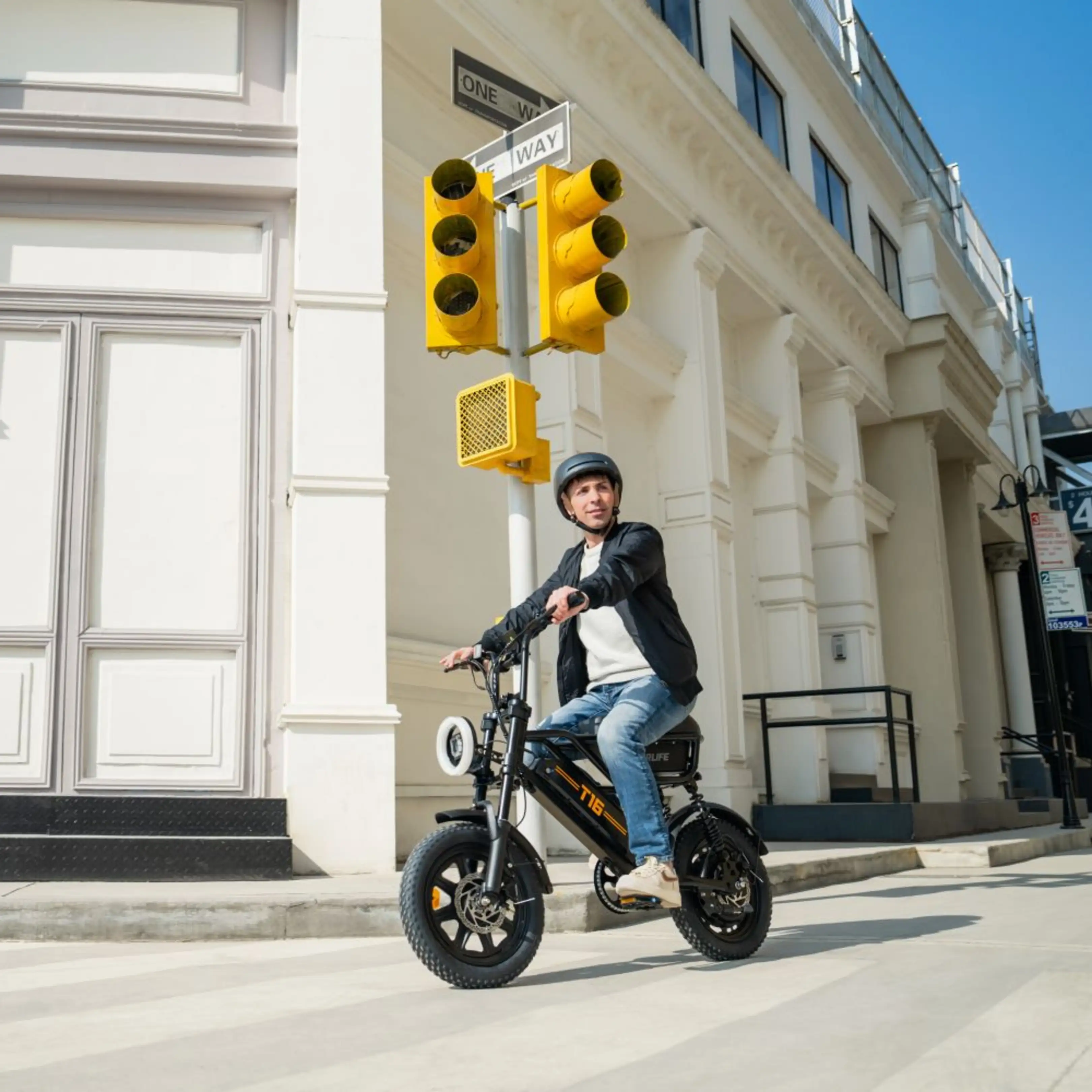 Ein Mann mit Helm fährt vor einem historischen Gebäude ein schwarzes Elektrofahrrad.