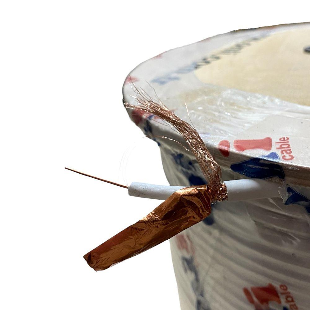 Kablo makarasının önünde açıkta kalan bakır telli ve korumalı beyaz bir kablo.