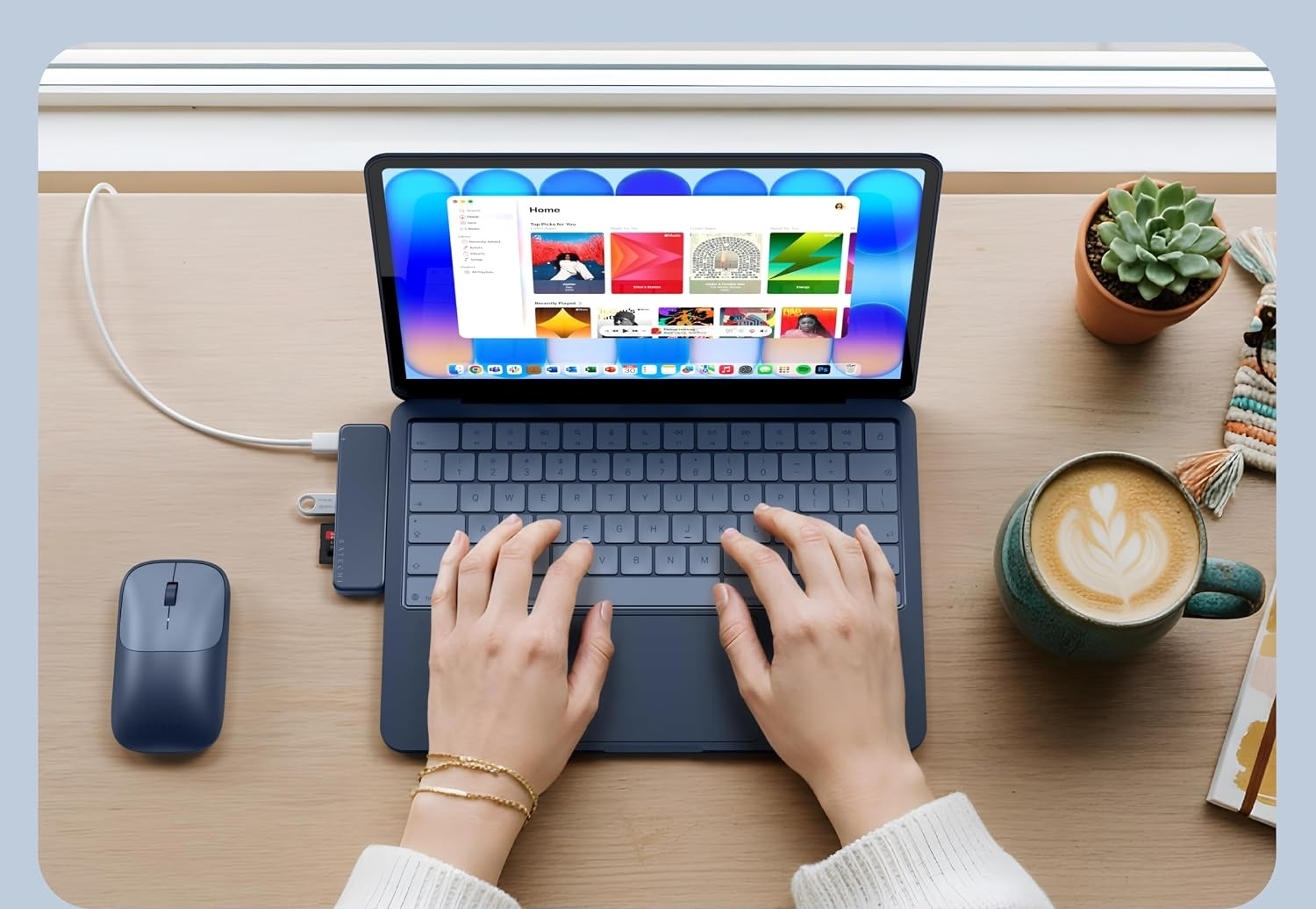 Hände tippen auf einer blauen Tablet-Tastatur, neben einer Kaffeetasse, einer Maus und einer Topfpflanze auf dem Holzschreibtisch.