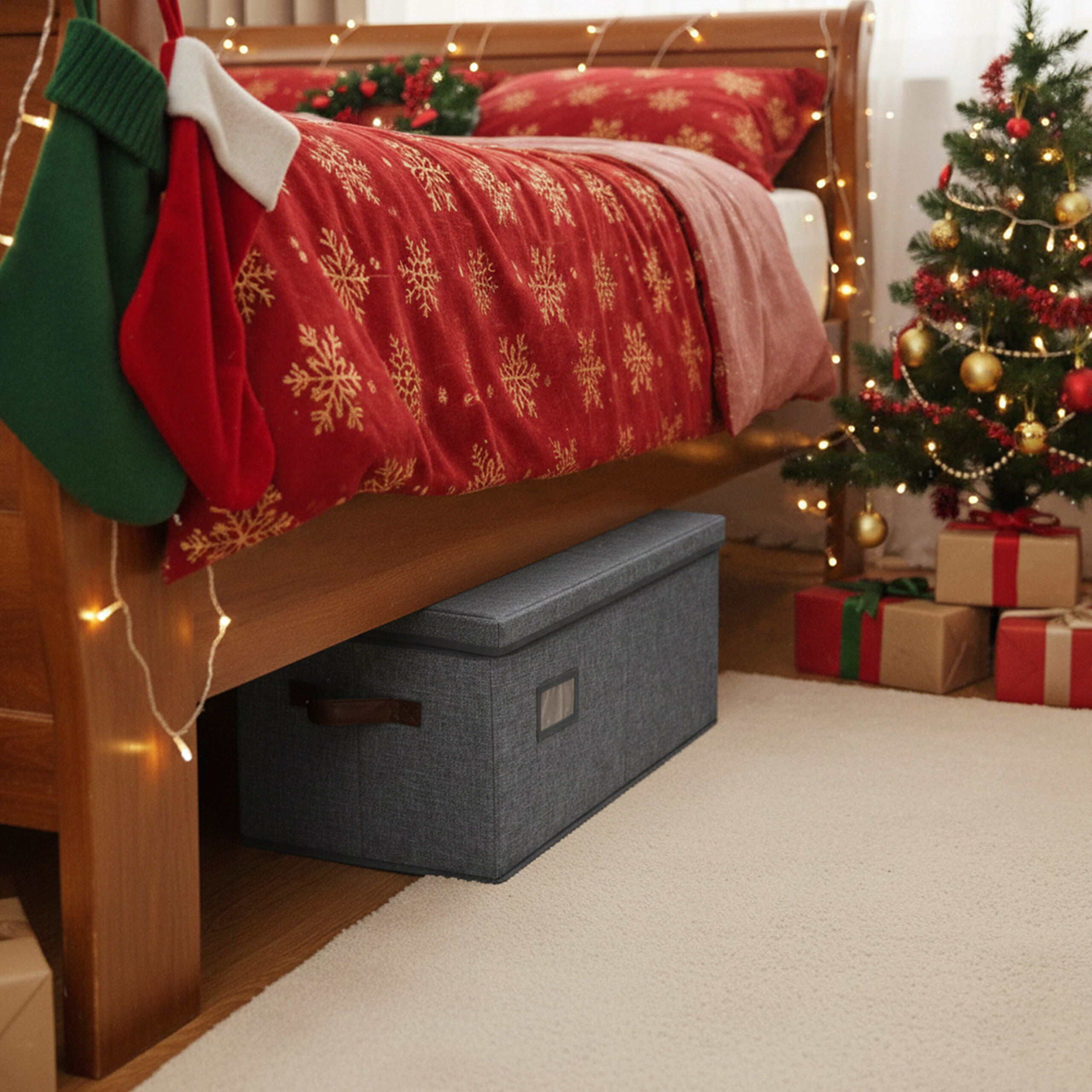 Eine graue Aufbewahrungsbox unter einem festlich geschmückten Bett mit Weihnachtsbaum und Geschenken.