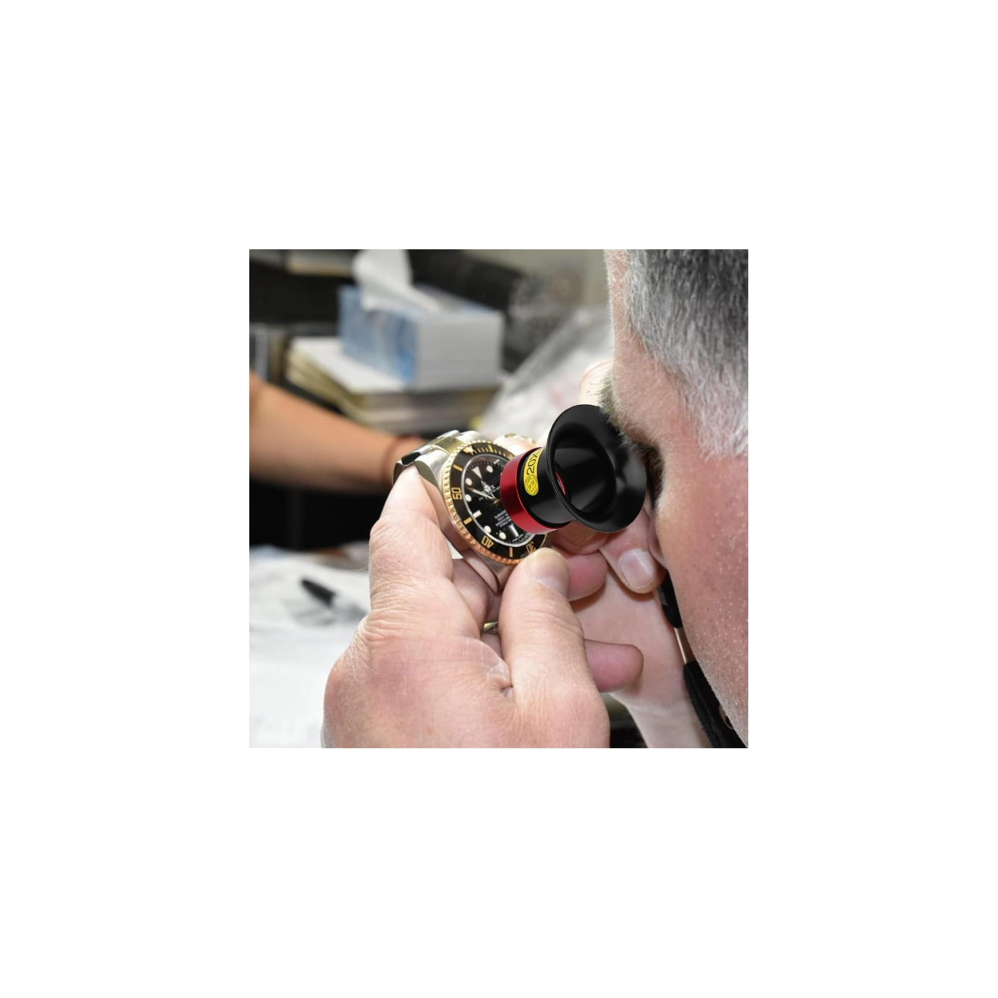 Ein Juwelier untersucht eine Uhr genau mit einer Lupe.