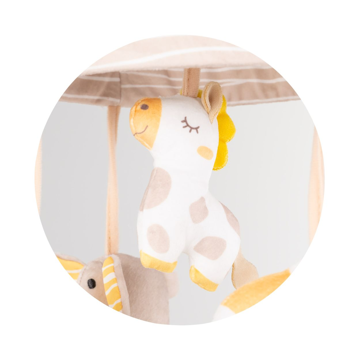 Ein Plüsch-Giraffen-Anhänger an einem Babymobilé mit weichen Beigetönen.