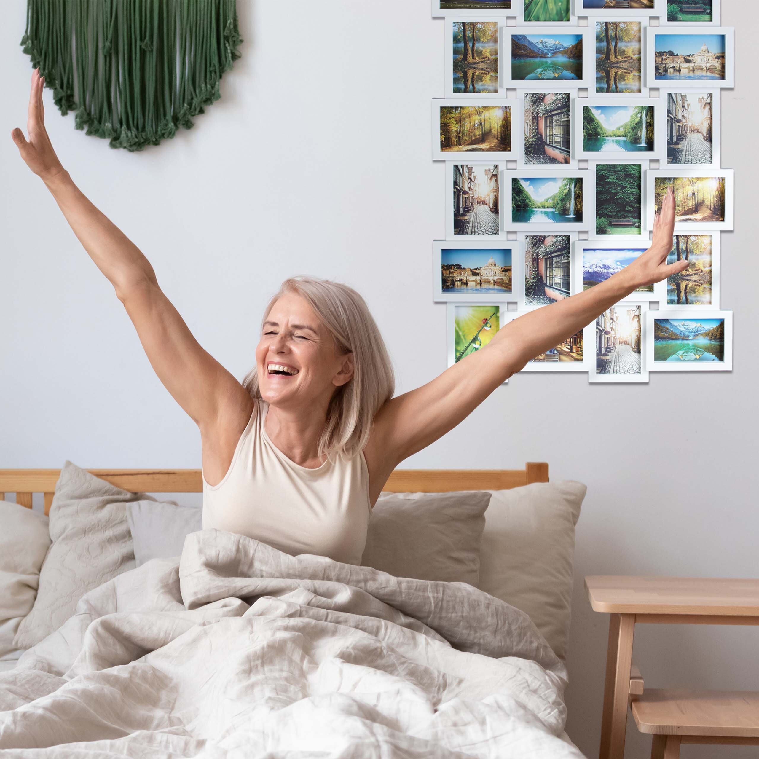 Eine lächelnde ältere Frau streckt sich im Bett mit erhobenen Armen neben einer Fotocollage.