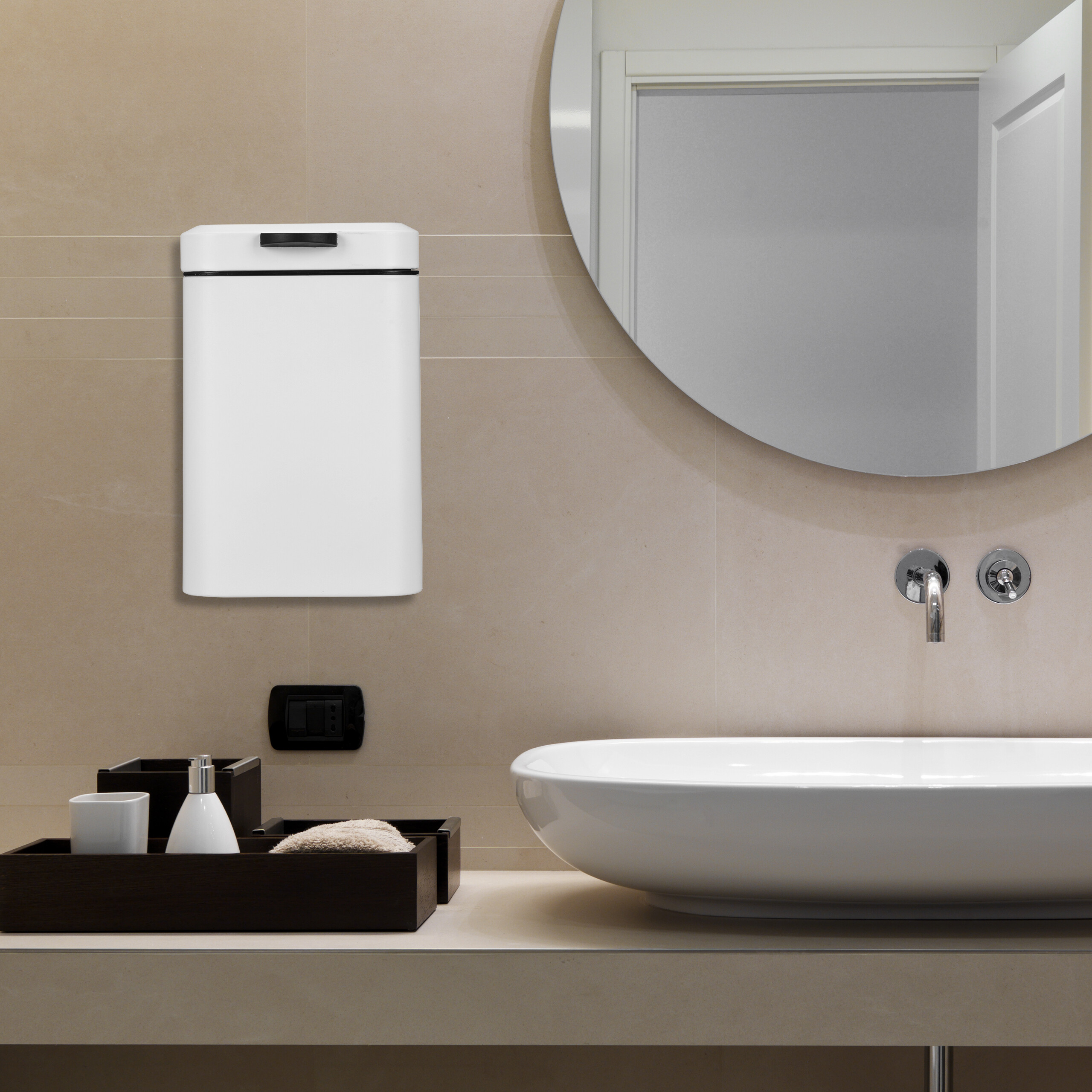 Moderne Badezimmereinrichtung mit weißem Mülleimer an der Wand, Waschbecken und rundem Spiegel.