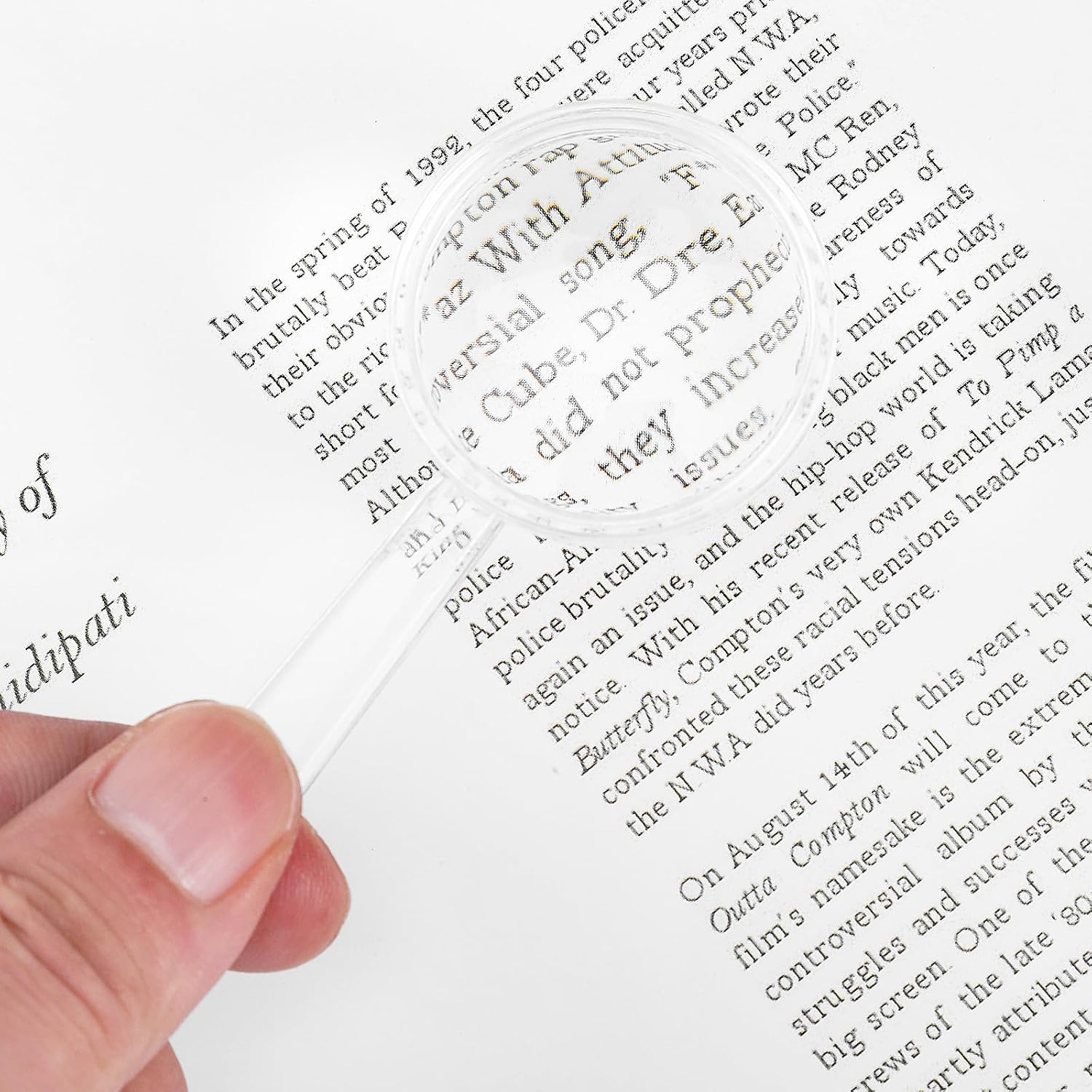 Eine Hand hält eine Lupe über eine gedruckte Buchseite mit Text.