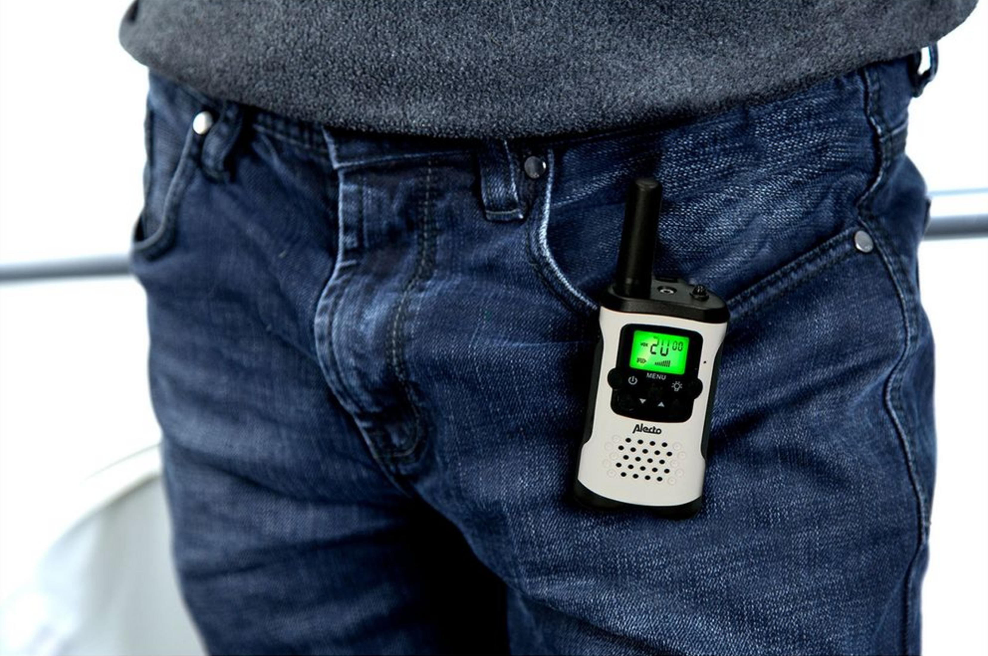 Un walkie-talkie Alecto blanco y negro sujeto al bolsillo delantero derecho de unos vaqueros azules.