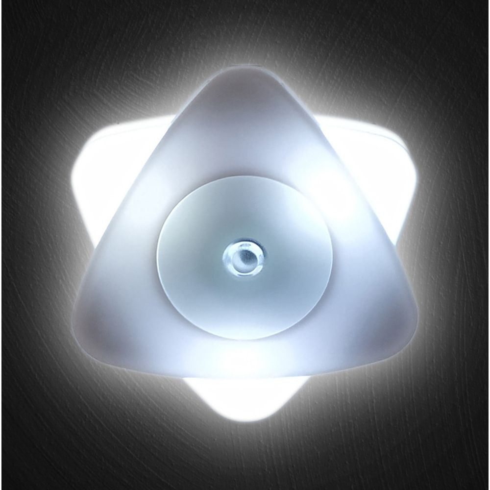 Een witte driehoekige led-lamp met een ronde knop in het midden schijnt tegen een donkere muur.