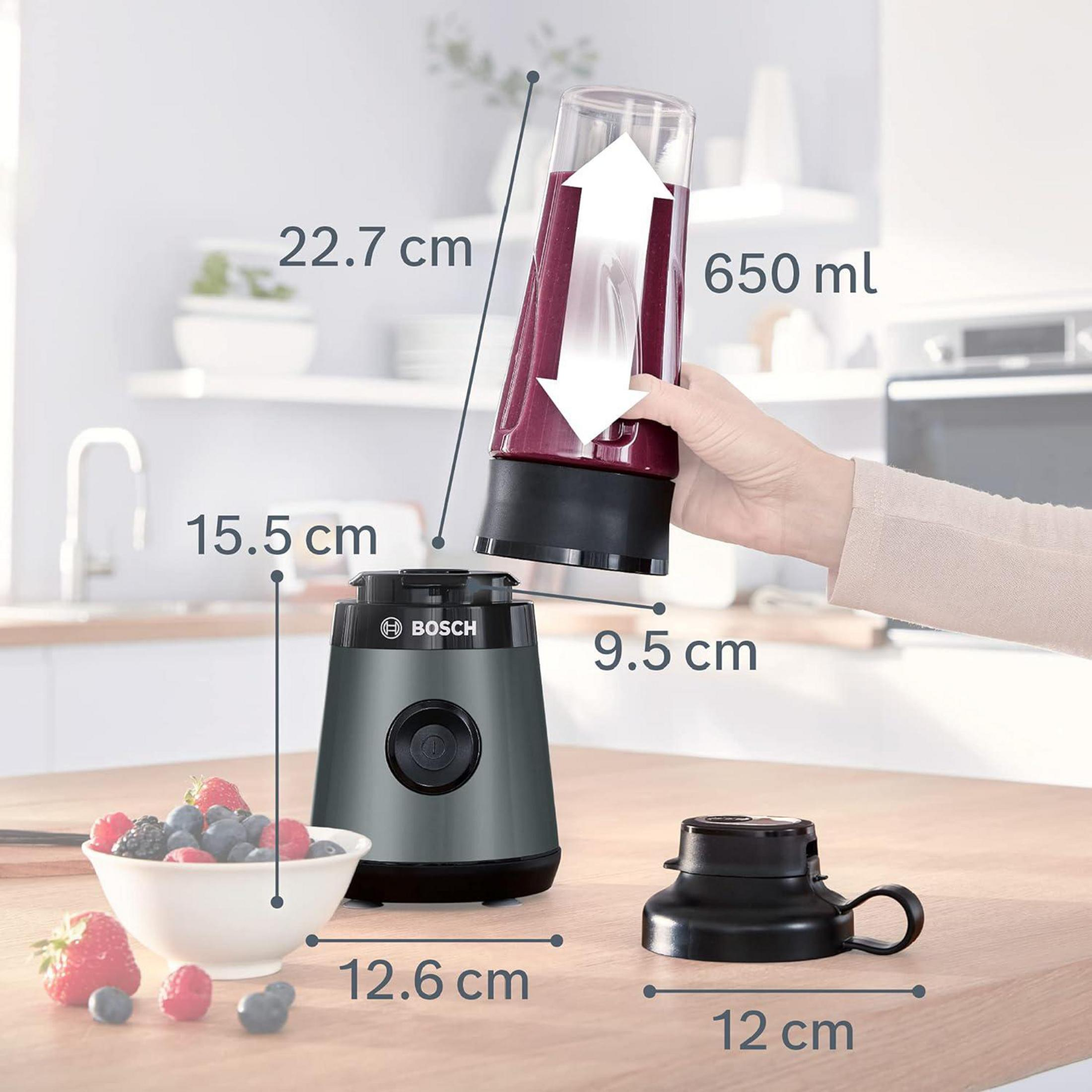 Un blender Bosch avec dimensions, un gobelet rempli de smoothie rouge, des baies fraîches et une cuisine en fond.