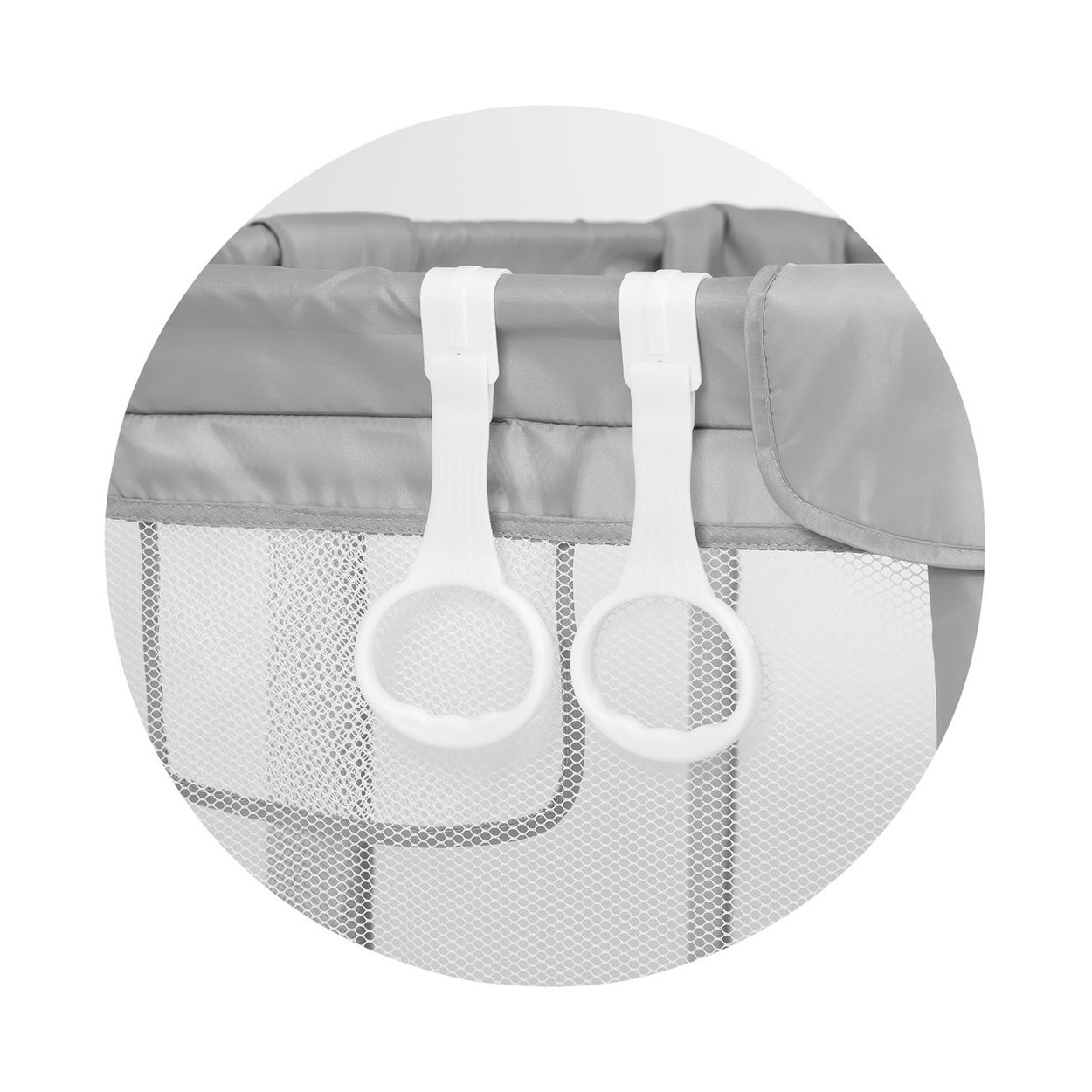Zwei weiße Kunststoff-Haltegriffe hängen am Rand eines grauen Reisebetts.