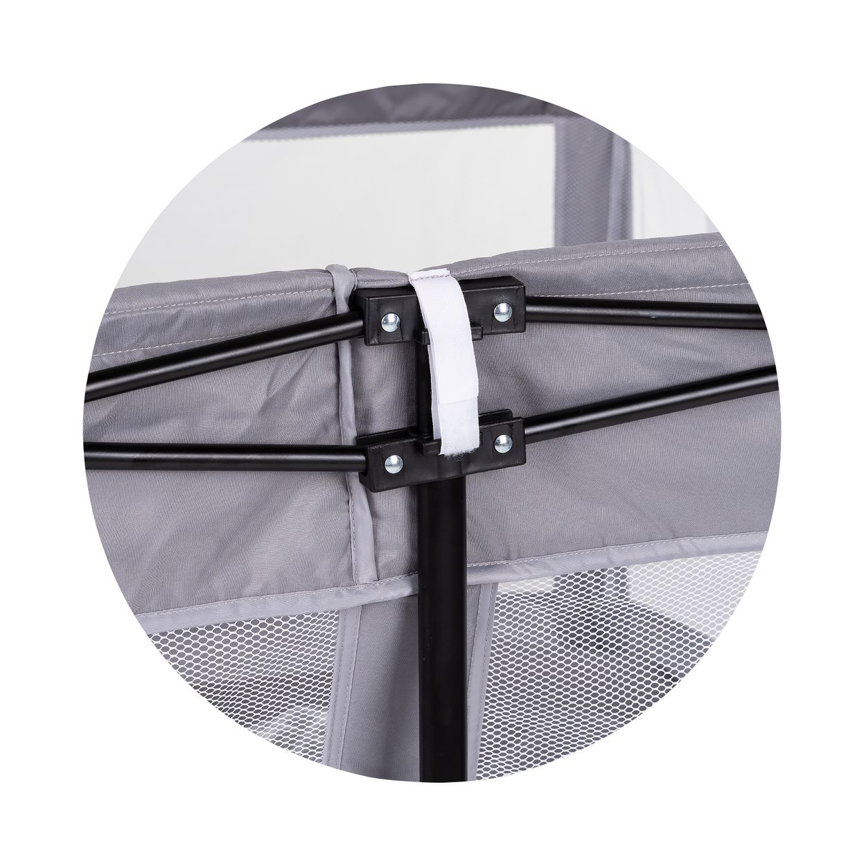 Nahaufnahme eines grauen Reisebetts mit schwarzem Metallgestänge, weißen Verbindungsstücken und Klettband.