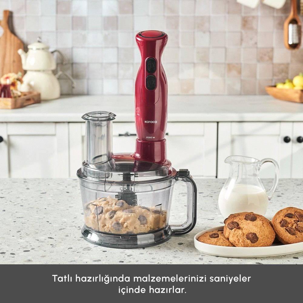 Mutfak tezgahında kurabiye hamurlu kabın üzerinde kırmızı el blenderi, yanında süt ve kurabiyeler.