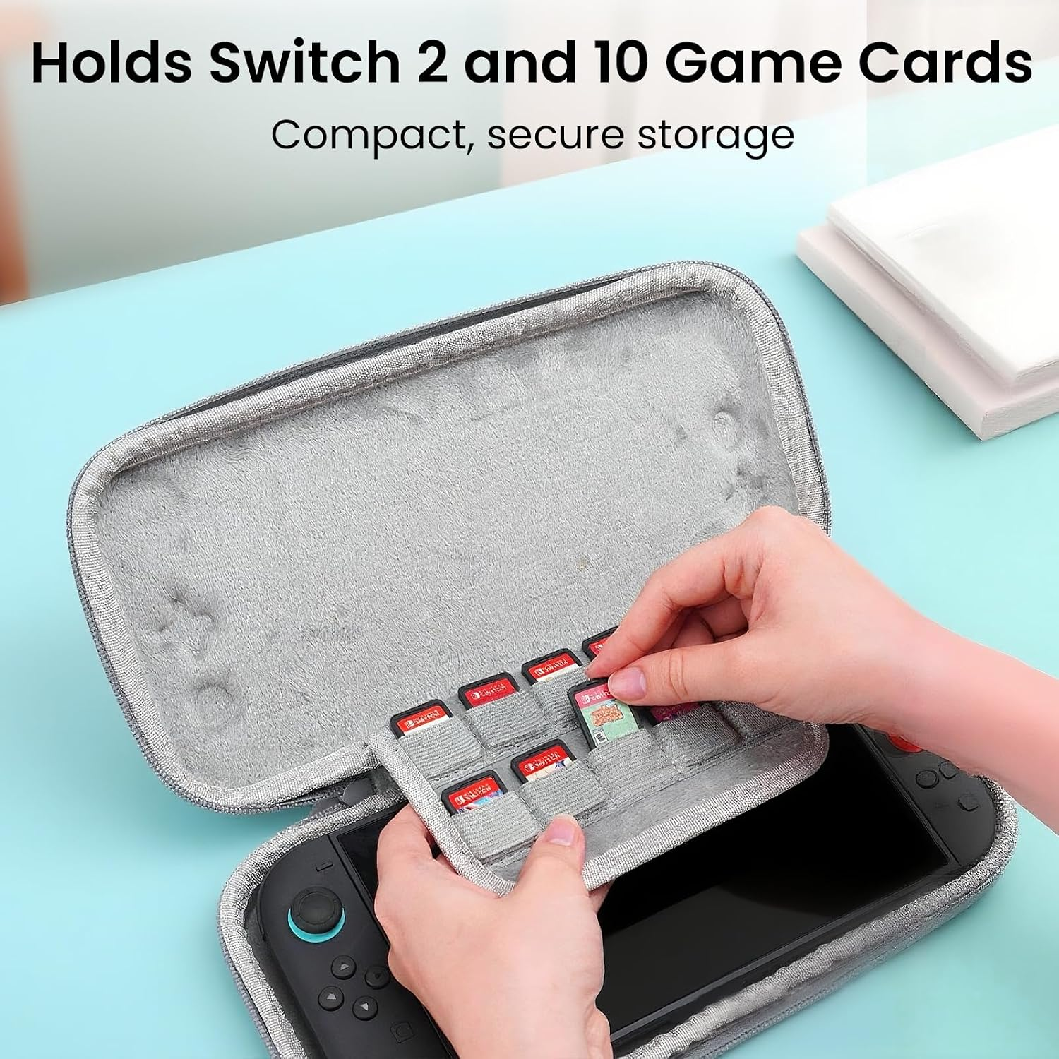 Hände verstauen eine Spielkarte in der grauen Hülle einer Nintendo Switch auf einem hellblauen Tisch.