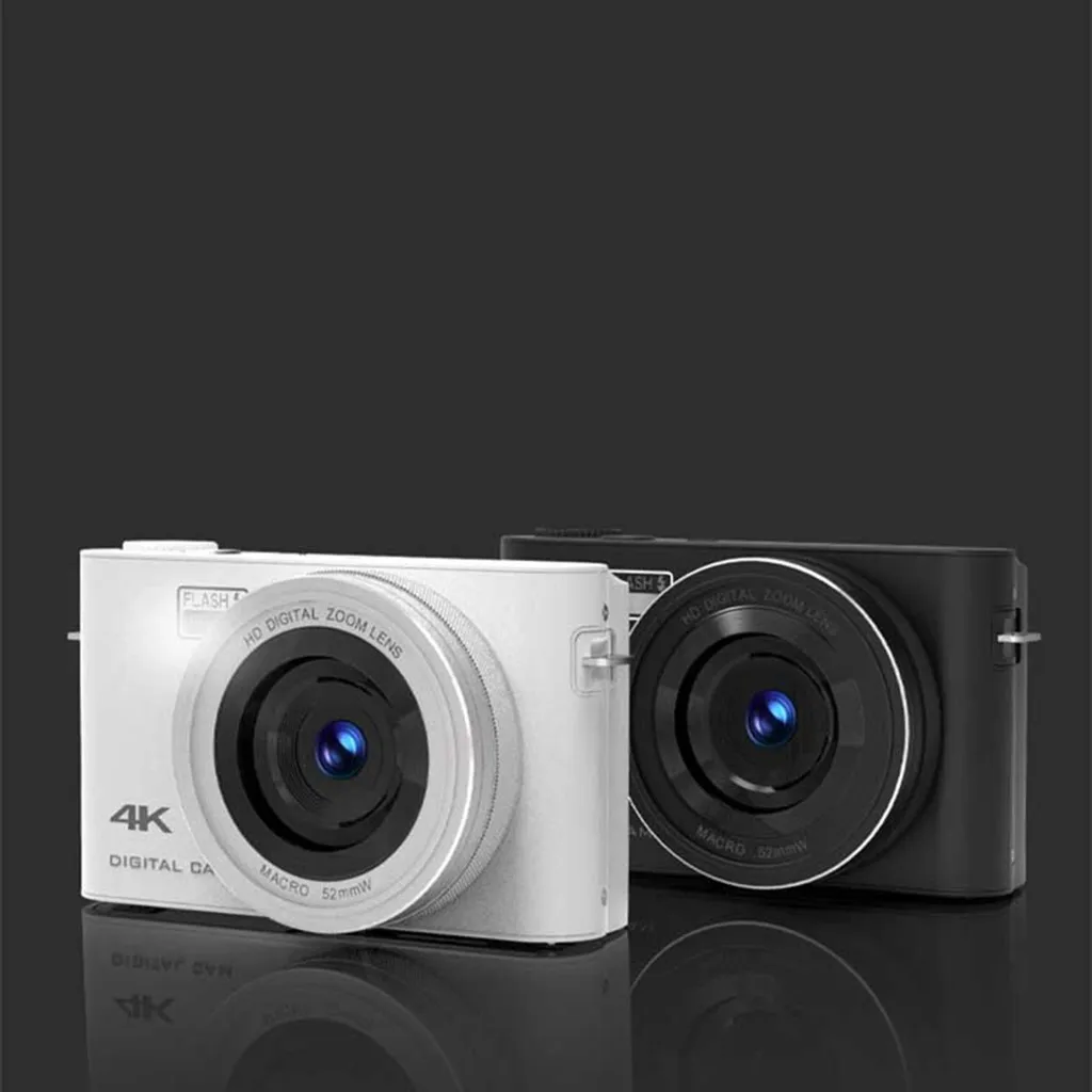 Zwei kompakte 4K-Digitalkameras in Weiß und Schwarz mit großen Makroobjektiven stehen nebeneinander vor dunklem Hintergrund.