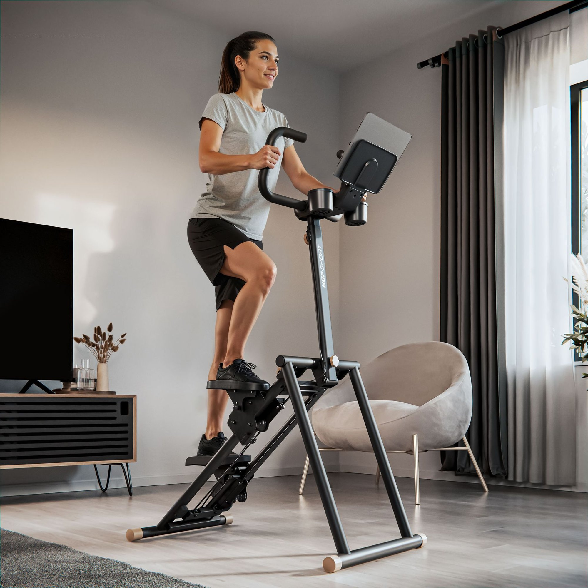 Eine Frau in Sportkleidung trainiert zu Hause auf einem schwarzen Stepper vor einem Fenster.
