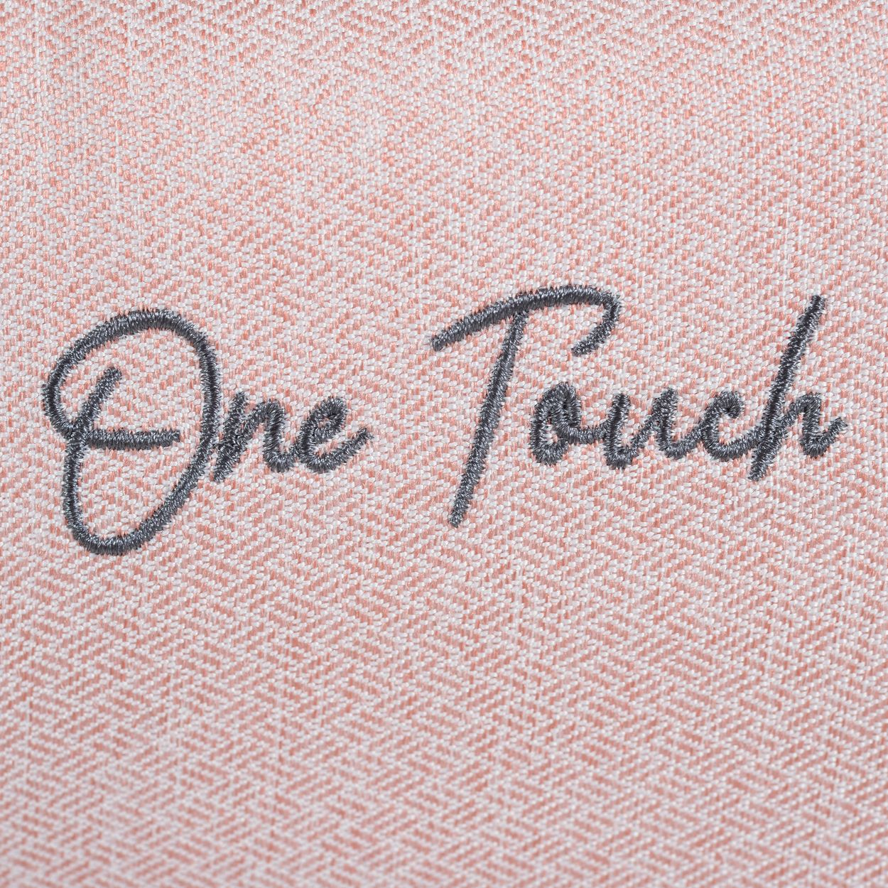 Auf einem hellrosa strukturierten Stoff steht die graue Aufschrift One Touch in Schreibschrift.