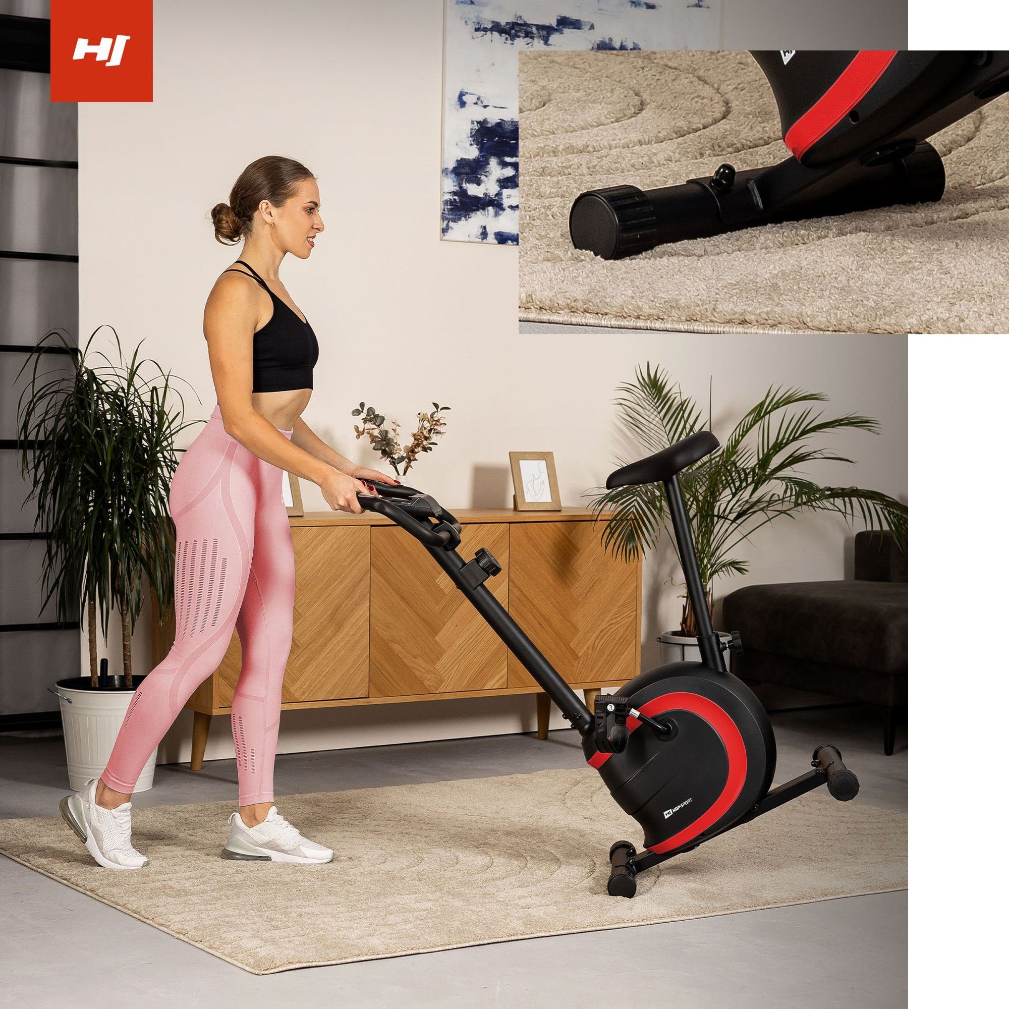 Eine Frau in rosa Leggings und schwarzem Oberteil stellt ein Heimfahrrad auf einem Teppich ein.