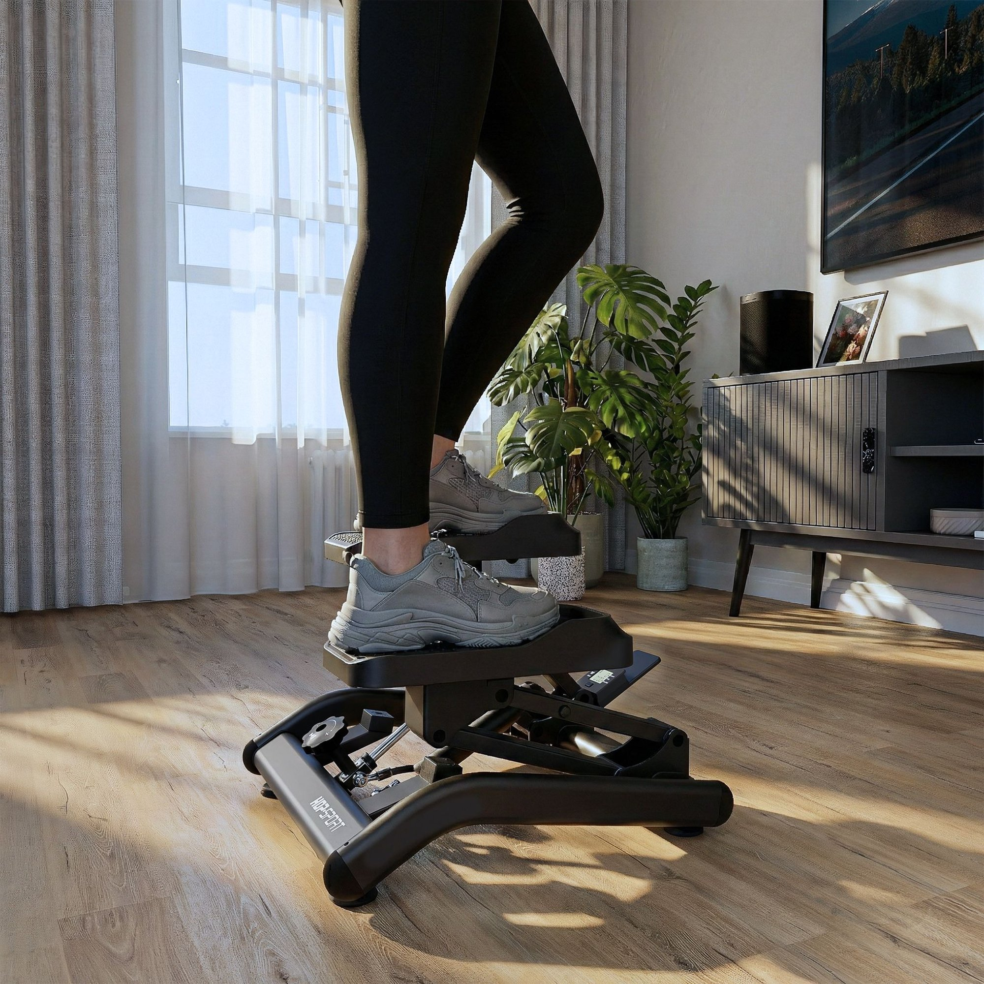 Eine Person in schwarzen Leggings und grauen Sneakers trainiert auf einem schwarzen Mini-Stepper in einem sonnigen Wohnzimmer.