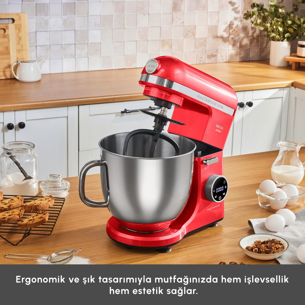 Ahşap mutfak tezgahı üzerinde yumurta, un ve kurabiye gibi malzemelerle kırmızı stand mikser.