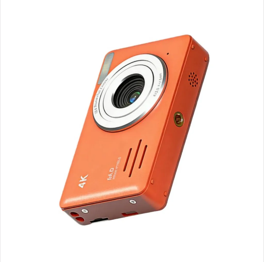 Eine kompakte orangefarbene 4K-Digitalkamera mit silbernem Objektivring auf weißem Hintergrund.